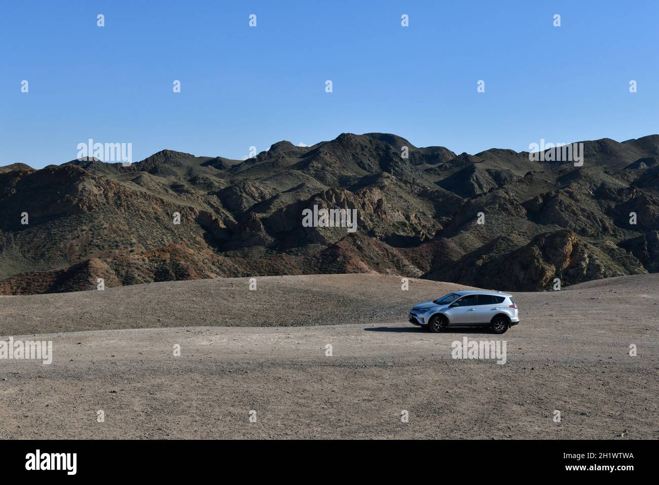 Silbernes Auto im Canyon, ungewöhnliche Beschaffenheit der Berge, Natur- und Technologiekonzept, blauer Himmel Stockfoto