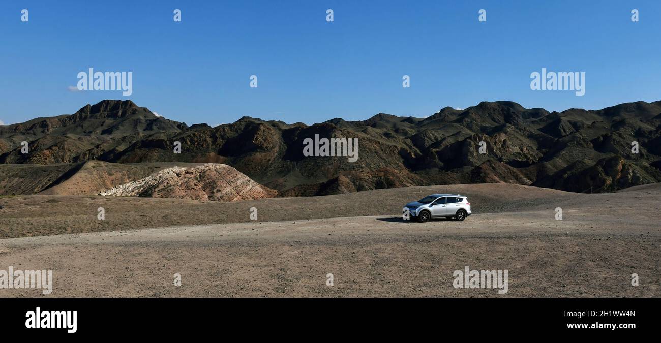 Silbernes Auto im Canyon, ungewöhnliche Beschaffenheit der Berge, Natur- und Technologiekonzept, blauer Himmel Stockfoto