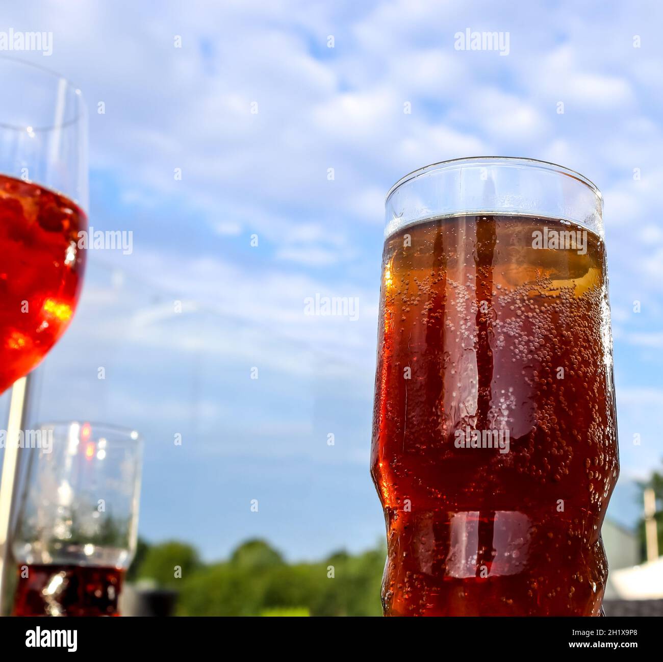 Erfrischende orange Sommer Cocktails mit Cola und Eis vor blauem Himmel Hintergrund. Stockfoto