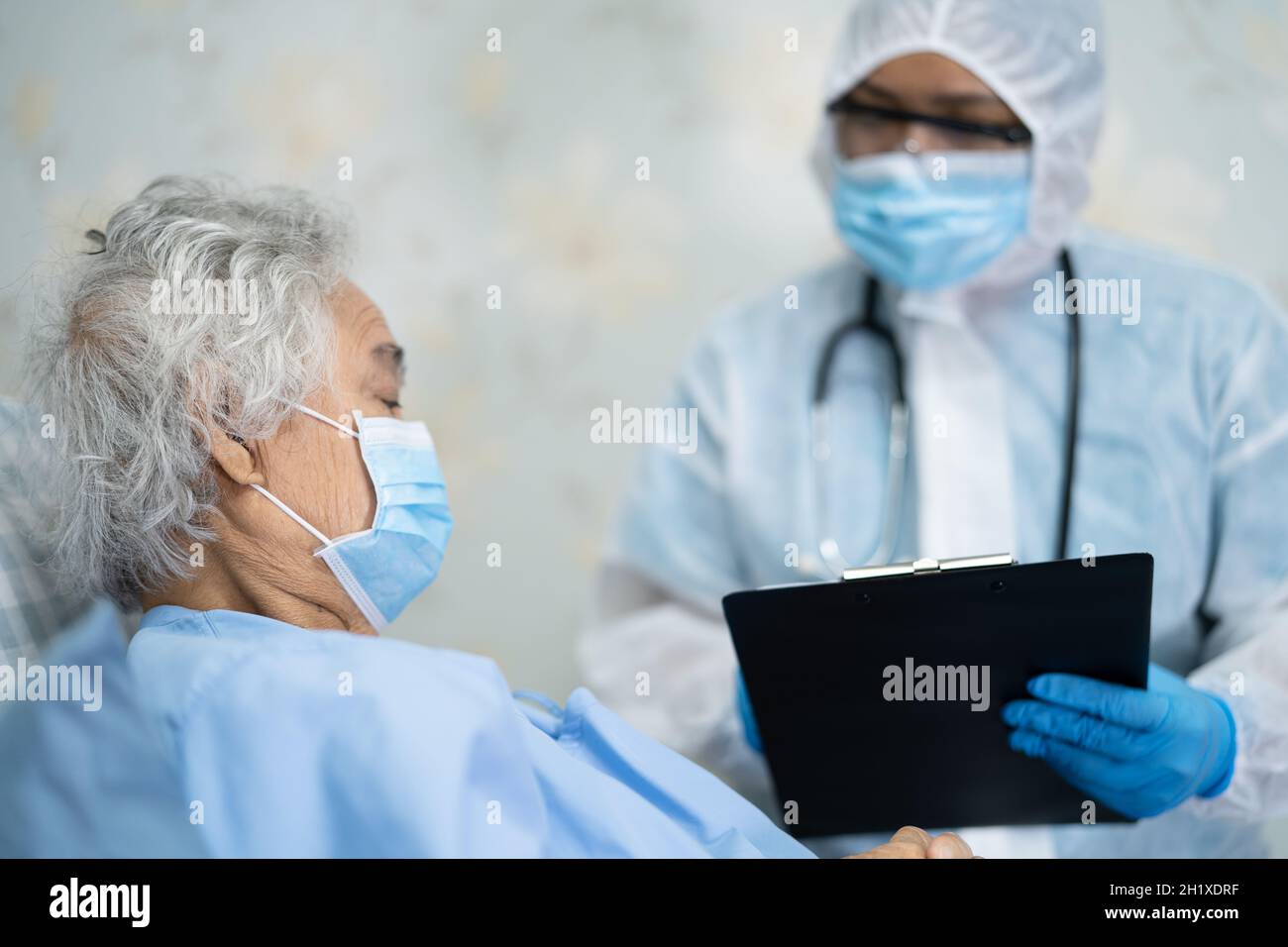 Asiatische Arzt trägt Gesichtsschutz und PSA Anzug neu normal Um den Patienten zu überprüfen schützen Sicherheit Infektion Covid-19 Coronavirus Ausbruch bei Quarantänepflege Stockfoto