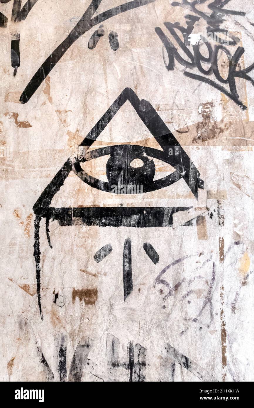 Illuminati-Logo an der Wand gemalt. 'Alle sehenden Auge' Gottes in der heiligen Geometrie Dreieck. Mauerwerk und Illuminaten-Symbol im Dreieck mit Lichtstrahl. Stockfoto