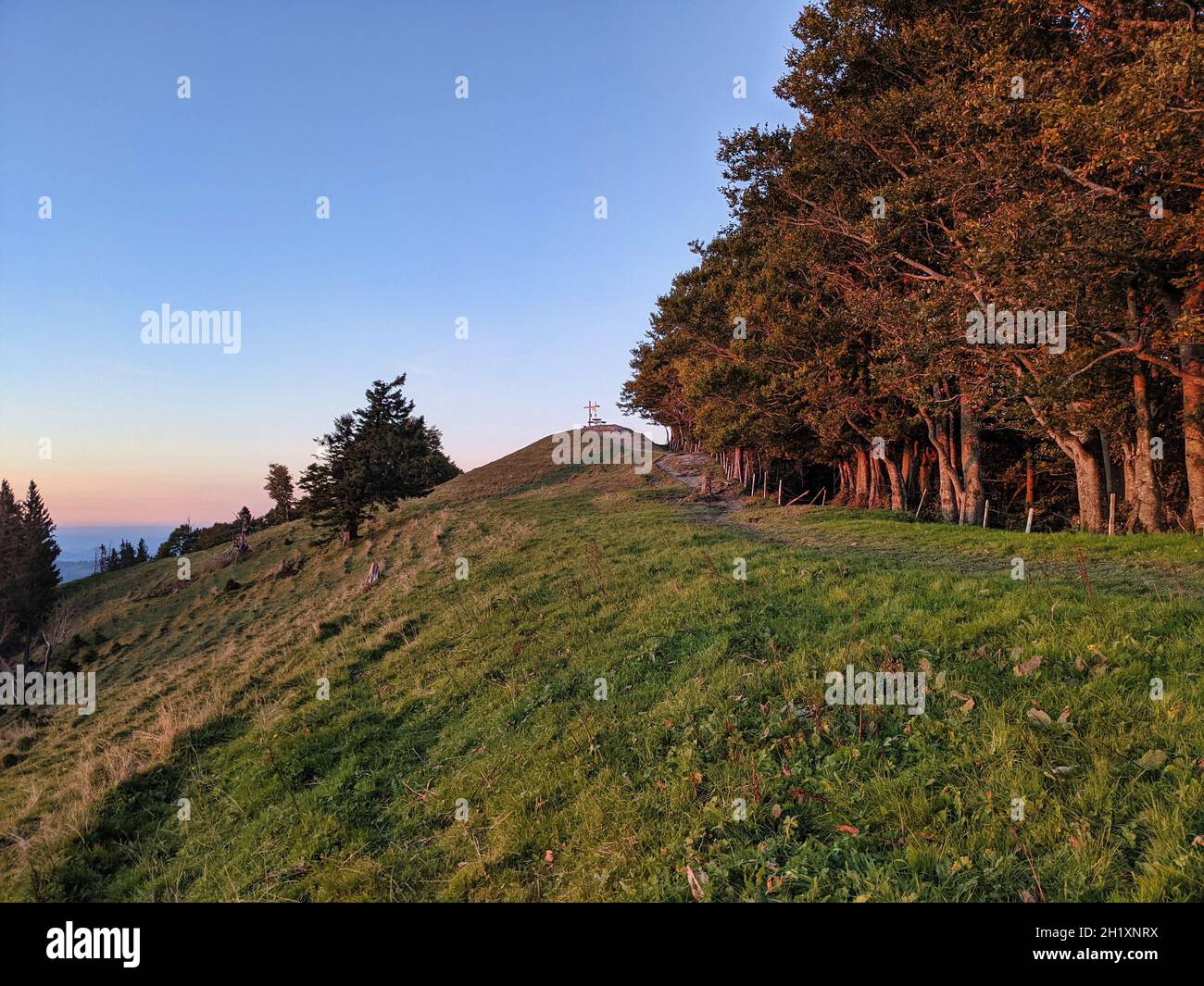 Wunderschöner Sonnenuntergang im Herbst. Schnebelhorn, Zürich. Die Sonnenstrahlen erleuchten die Wiese und die Bäume. Blick auf die alpen Stockfoto