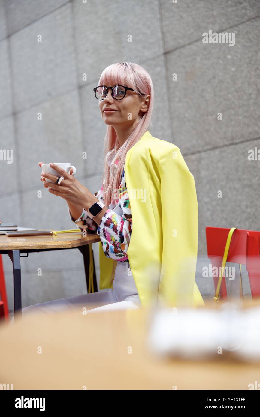 Modische Frau in Gläsern trinken Kaffee im Freien Stockfoto