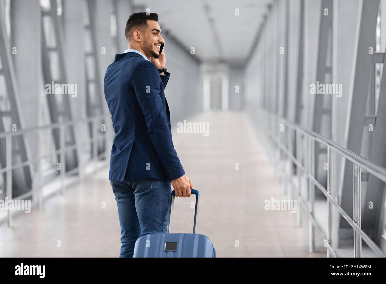 Nach Der Ankunft. Lächelnder Arabischer Geschäftsmann, Der Am Airport Gate Vorbeitelefoniert Stockfoto