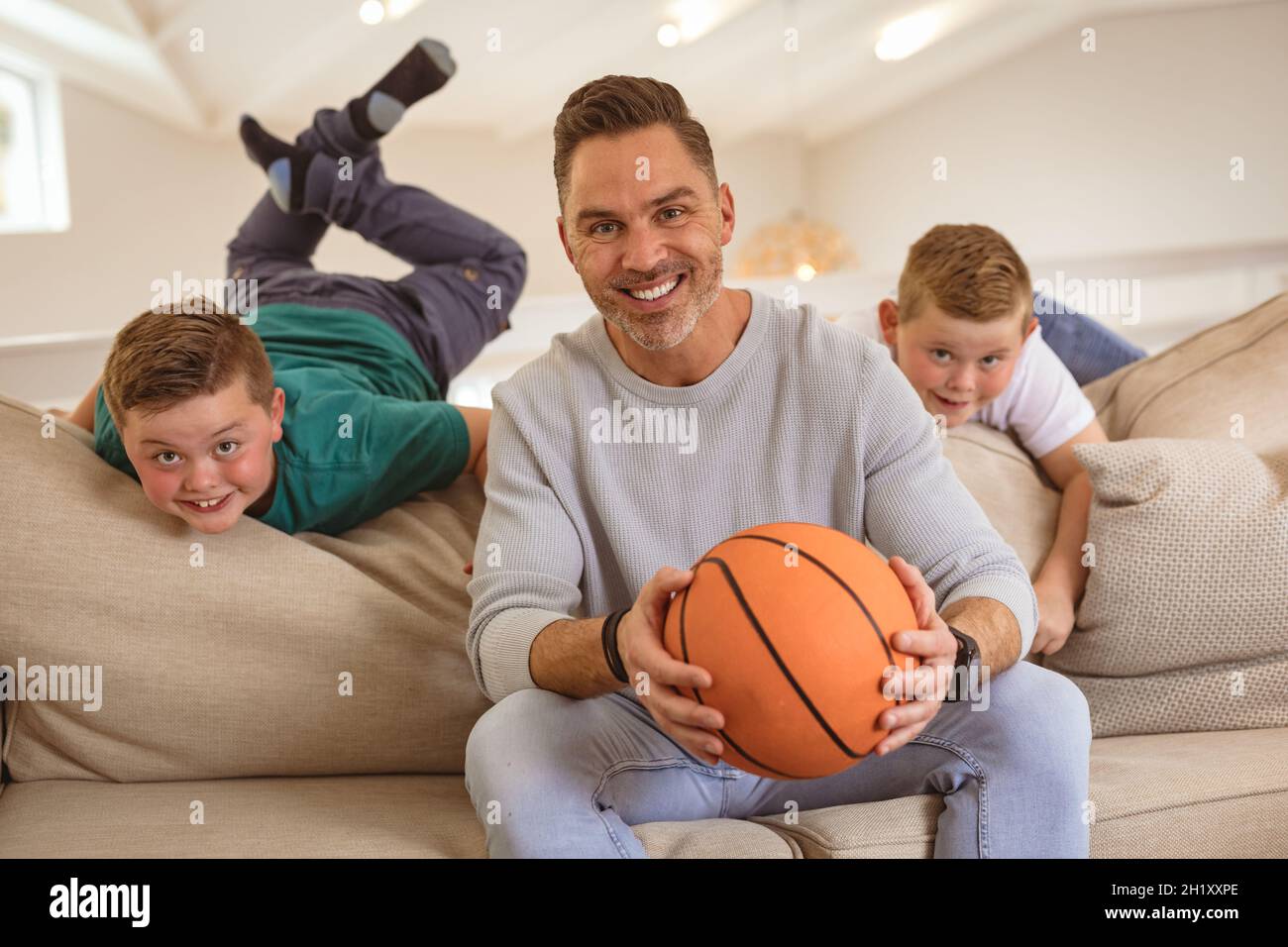 Porträt eines kaukasischen Vaters und zweier Söhne mit einem Lächeln im Basketball zu Hause Stockfoto