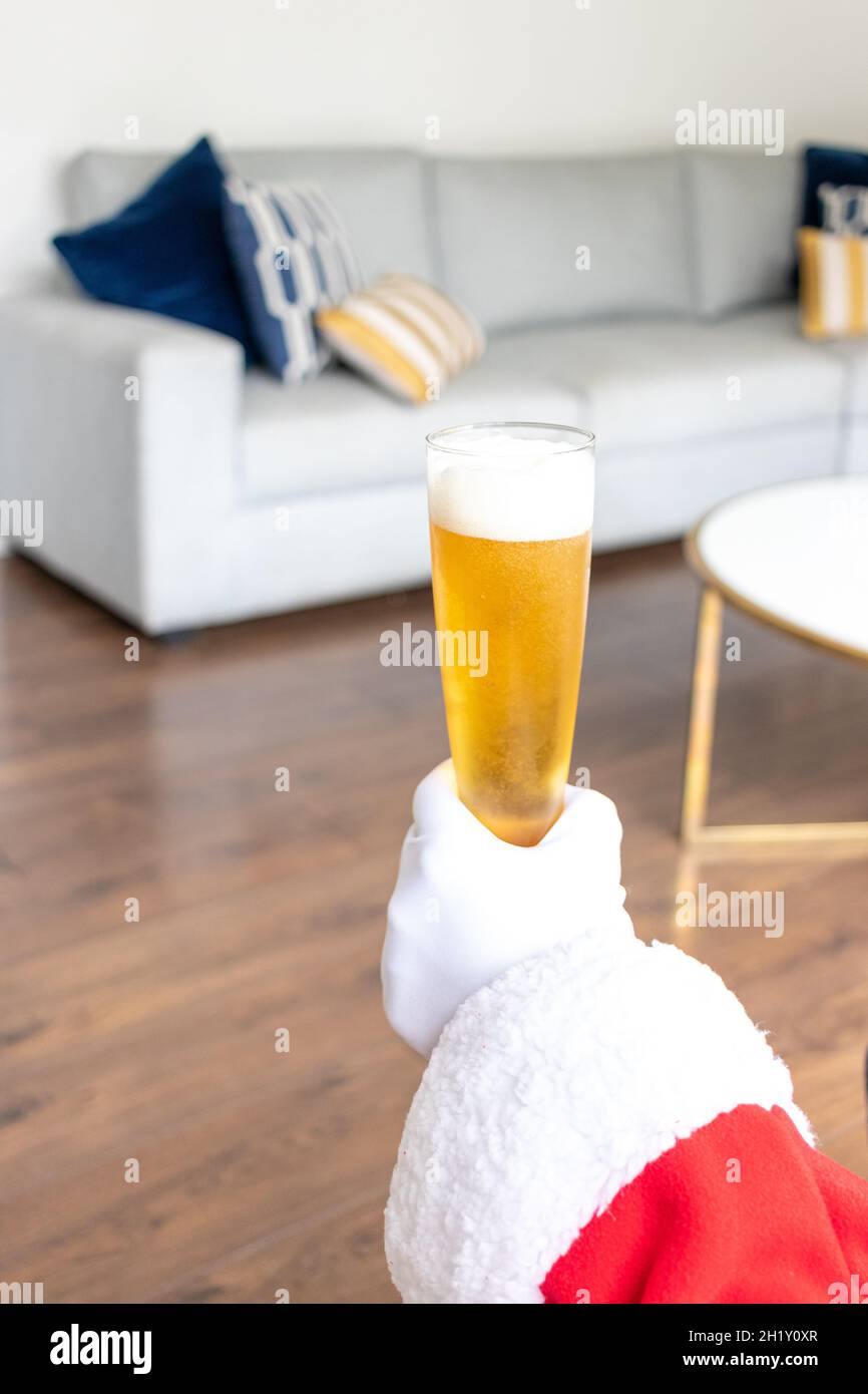 Weihnachtsmann bei einem Bier vor Weihnachten im Wohnzimmer Stockfoto