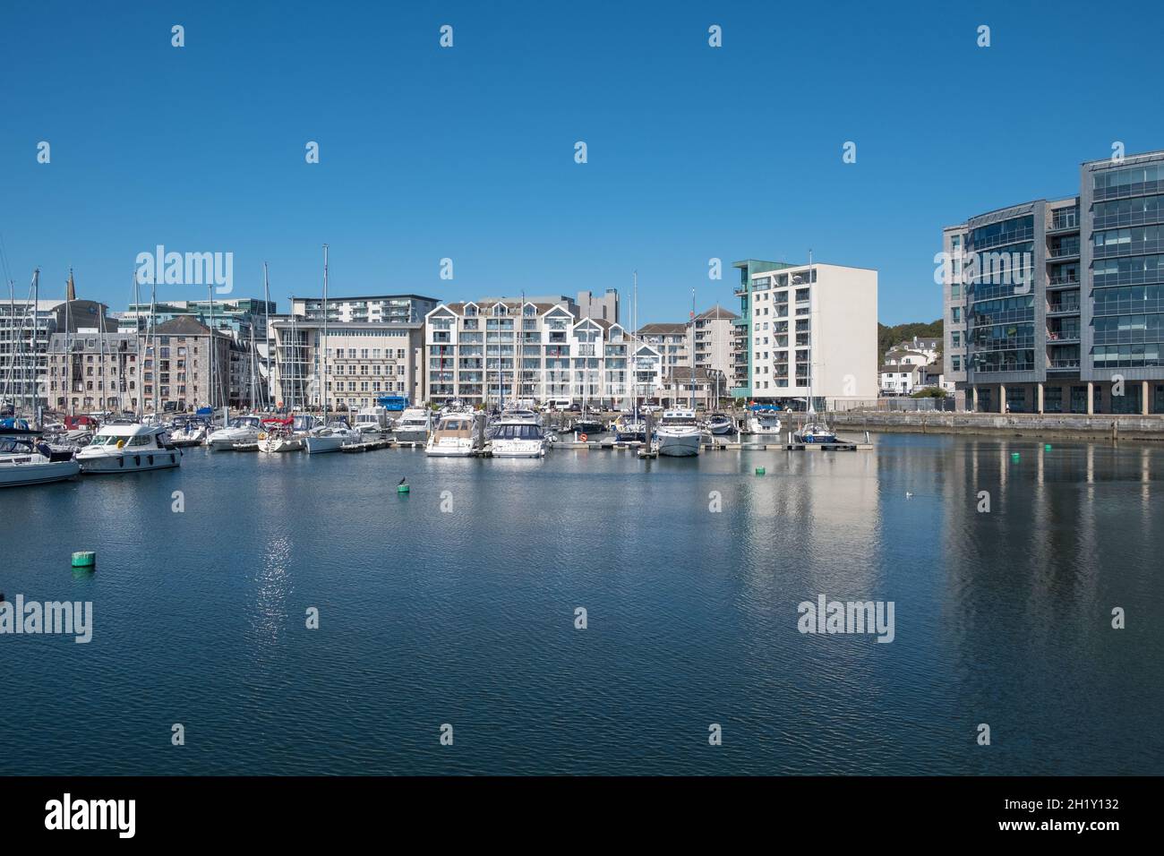 Apartmentblöcke mit Blick auf Yachten, die auf Pontons in Sutton Harbour, Plymouth, Devon festgemacht sind Stockfoto