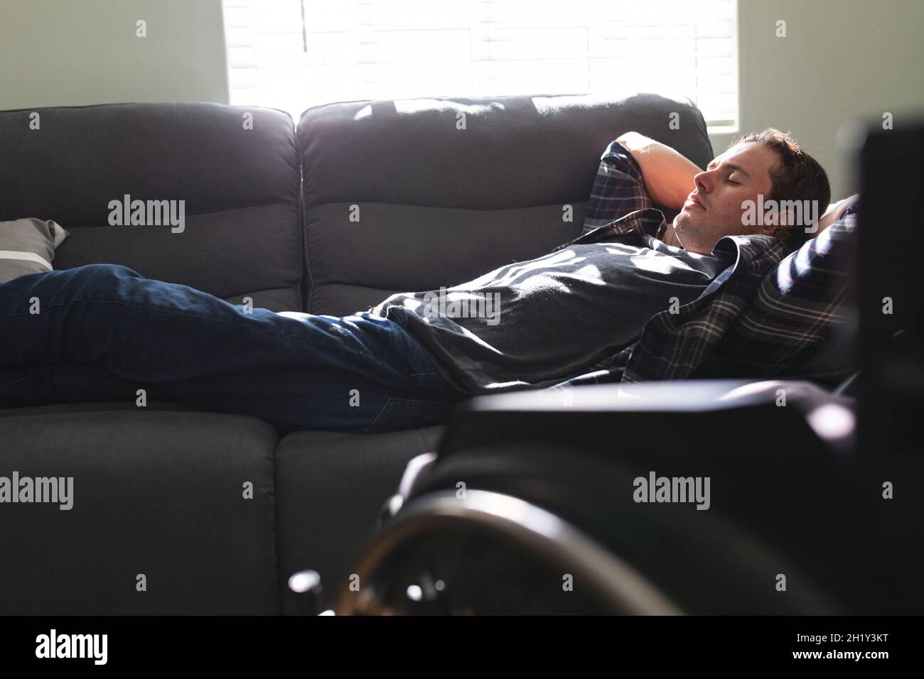 Kaukasischer behinderter Mann, der zu Hause ein Nickerchen auf der Couch macht Stockfoto