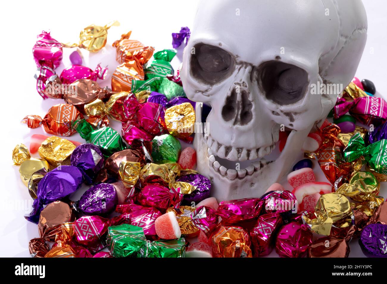 Komposition von halloween Lachschädel mit Trick or Treat Süßigkeiten auf weißem Hintergrund Stockfoto