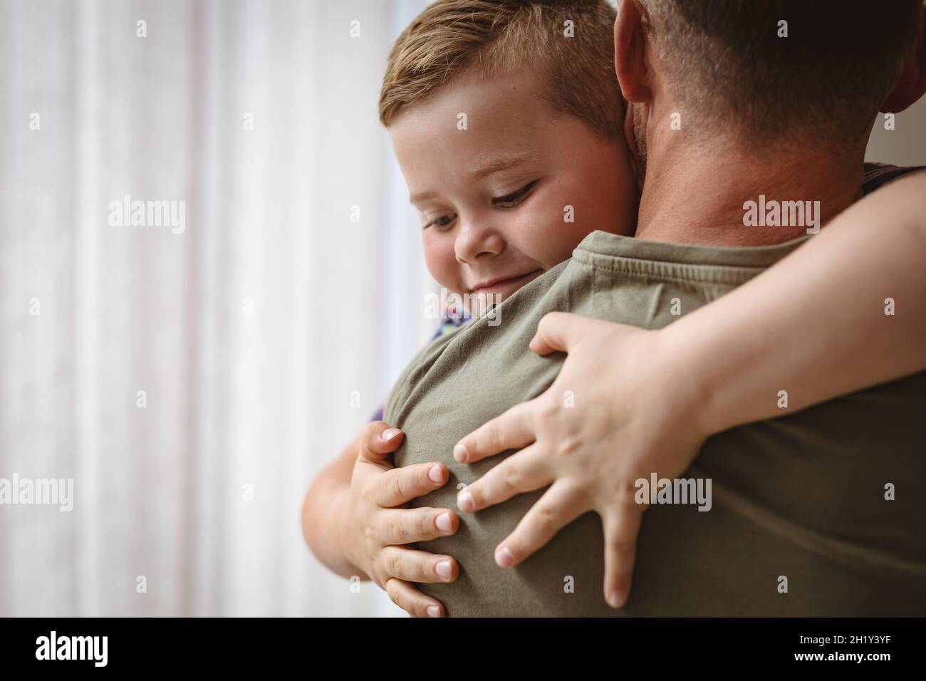 Nahaufnahme des kaukasischen Jungen, der seinen Vater zu Hause umarmt Stockfoto