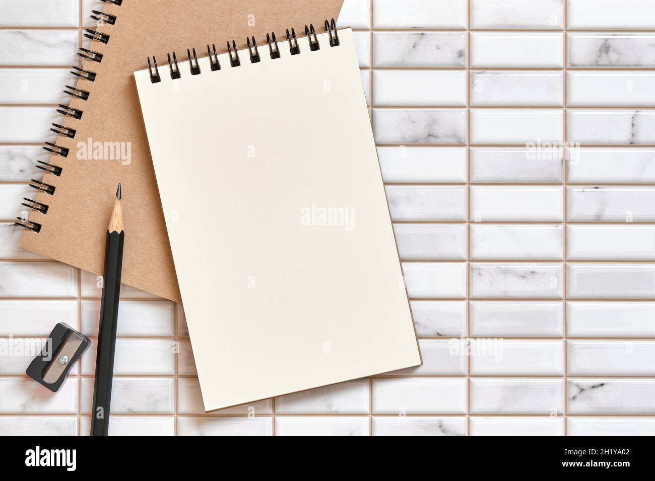 Offenes leeres Notizbuch, Bleistiftspitzer und Bleistift auf weißem Hintergrund, Flat Lay-Konzept, Copy Space for Text, Tabellenansicht oben. Stockfoto
