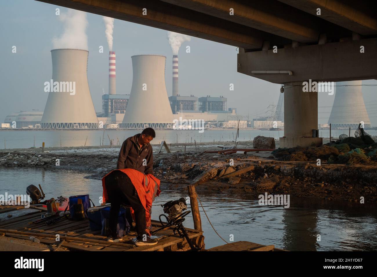 Zwei einheimische Fischer kommen aus dem Fischteich in der Nähe eines Kraftwerks in Tianjin, China, an Land. 19-Okt-2021 Stockfoto