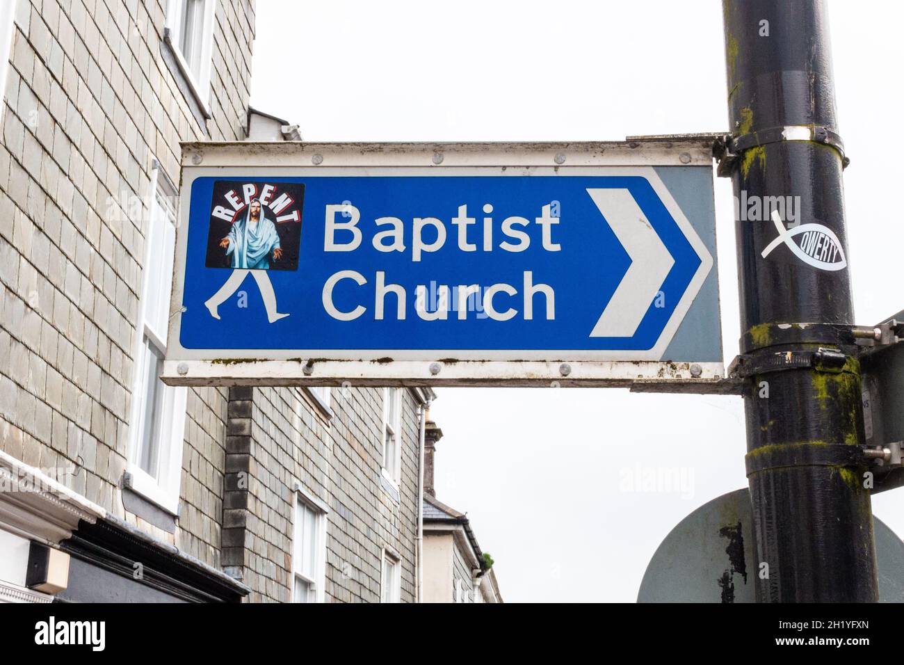 Ein Straßenschild, das den Weg zur Baptist Church in Kingsbridge, Devon, Großbritannien, zeigt. Ein Aufkleber von Jesus Christus mit der Botschaft „Buße“ ist daran festgeklebt worden. Stockfoto