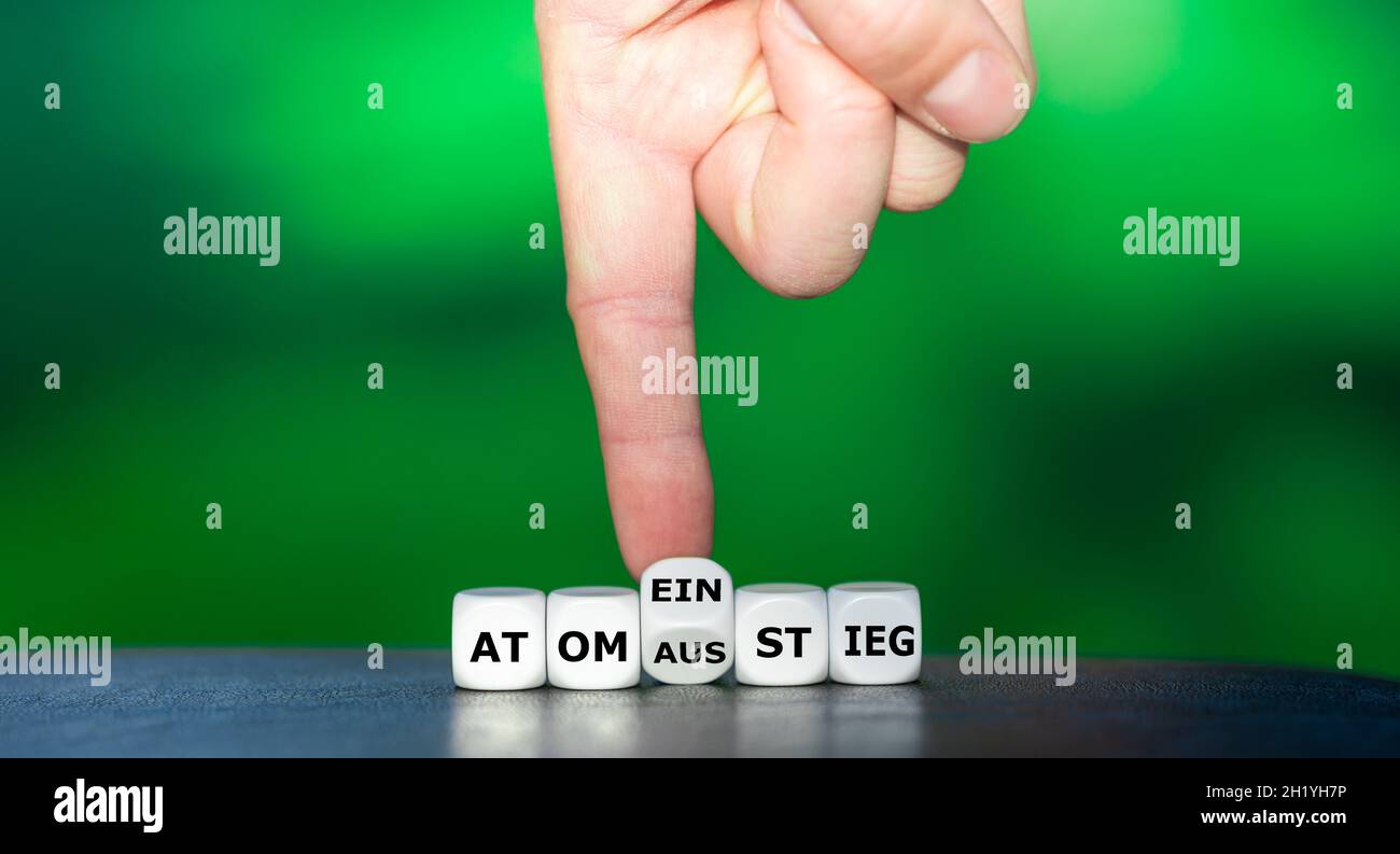 Die Hand dreht Würfel und ändert das deutsche Wort 'Atomausstieg' in 'Atomeinstieg'. Stockfoto