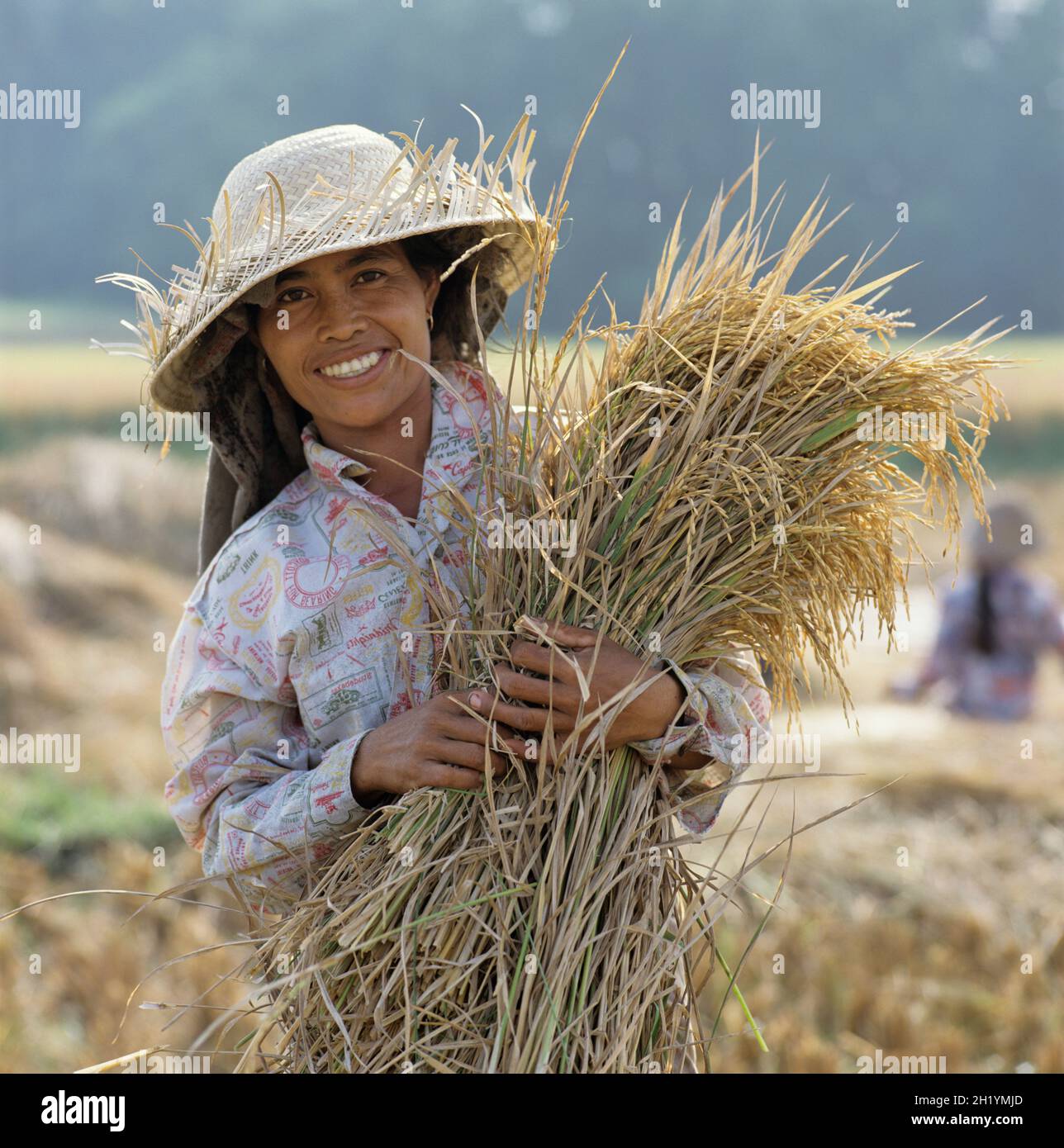 Junge Bali-Frau, die auf den Feldern arbeitet und in Strohhut posiert, Ubud, Bali, Indonesien, Südostasien Stockfoto