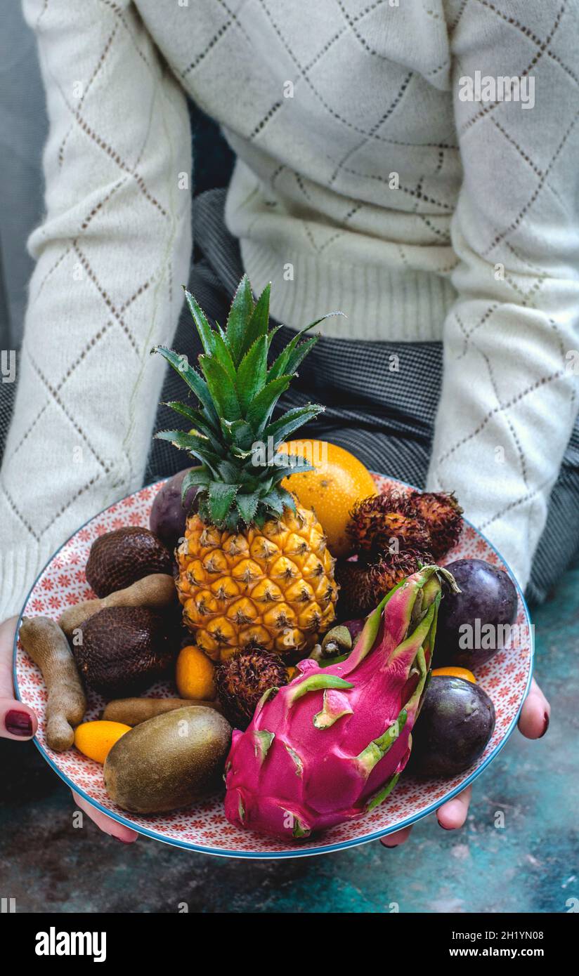Exotische Früchte auf einem Teller in den Händen Stockfoto
