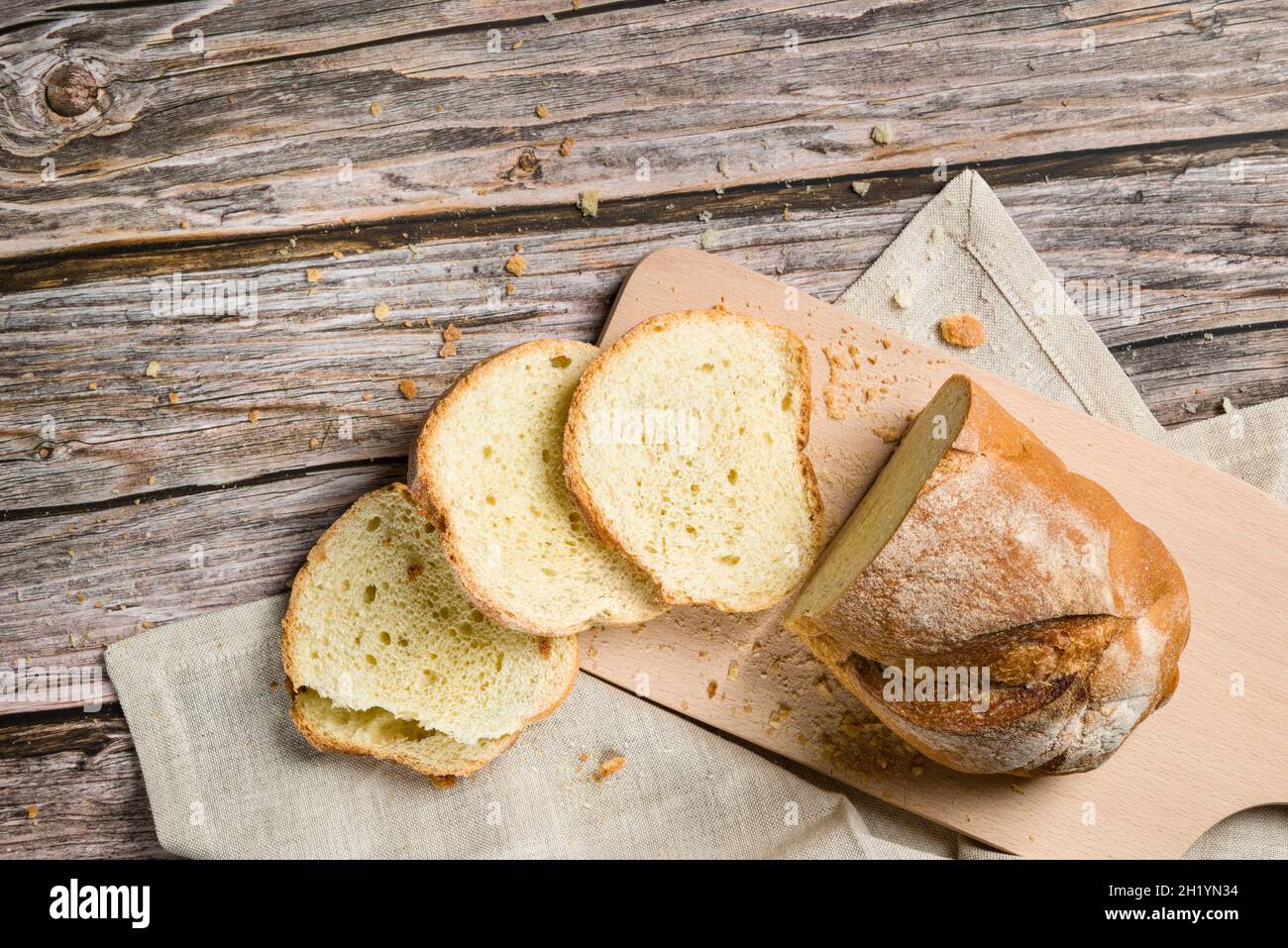Frisch geschnittenes Brot und Krümel auf einem Holztisch. Draufsicht Stockfoto