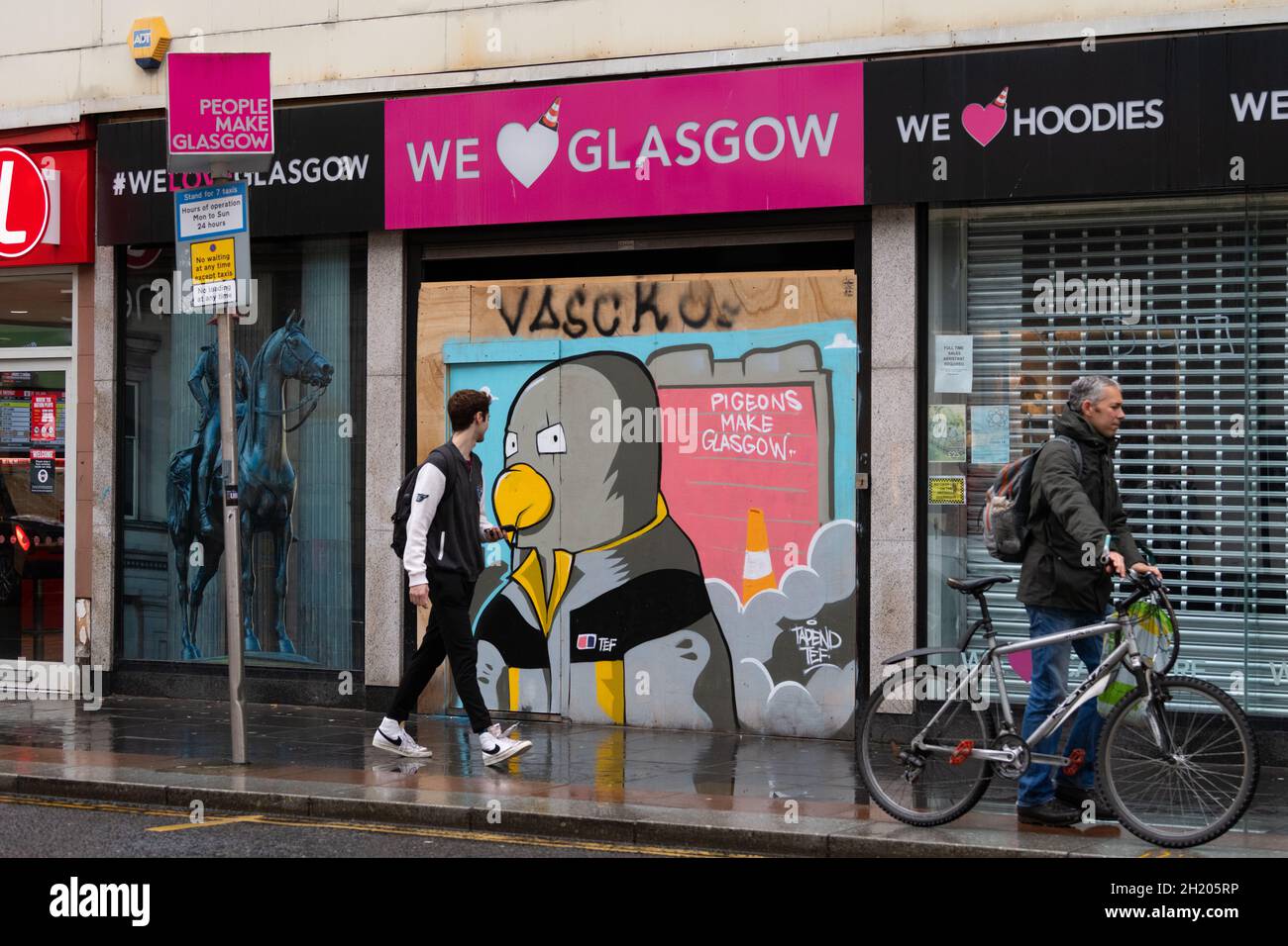 Tauben machen Glasgow zu einem Theaterstück über „People Make Glasgow“ - Graffiti im Stadtzentrum von Glasgow auf dem aufgepappten Laden „We love Glasgow“ von Tapendtef, Glasgow, Stockfoto