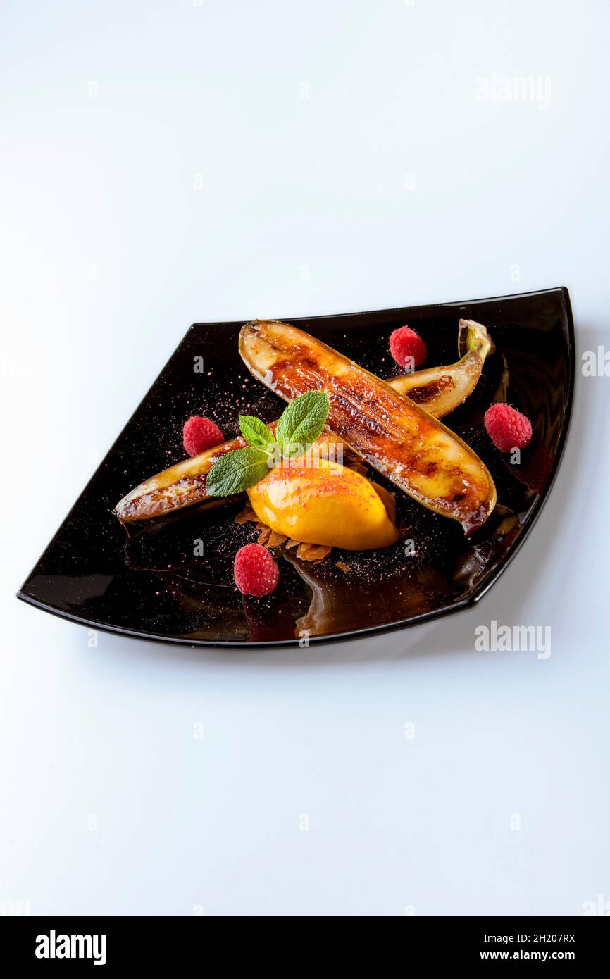 Eine gebratene Banane mit Passionsfrucht-Sorbet und Himbeeren Stockfoto