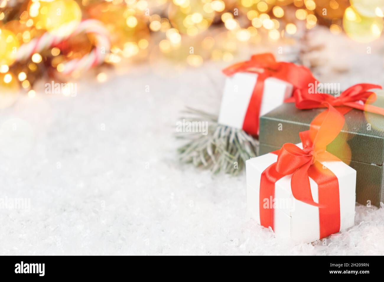 Schöne Weihnachtsgeschenke mit Kiefernzweig, Schnee und Bokeh Lichter auf dem Hintergrund mit Kopierraum. Postkarte, Rabattgutschein oder Verkaufskonzept. Stockfoto