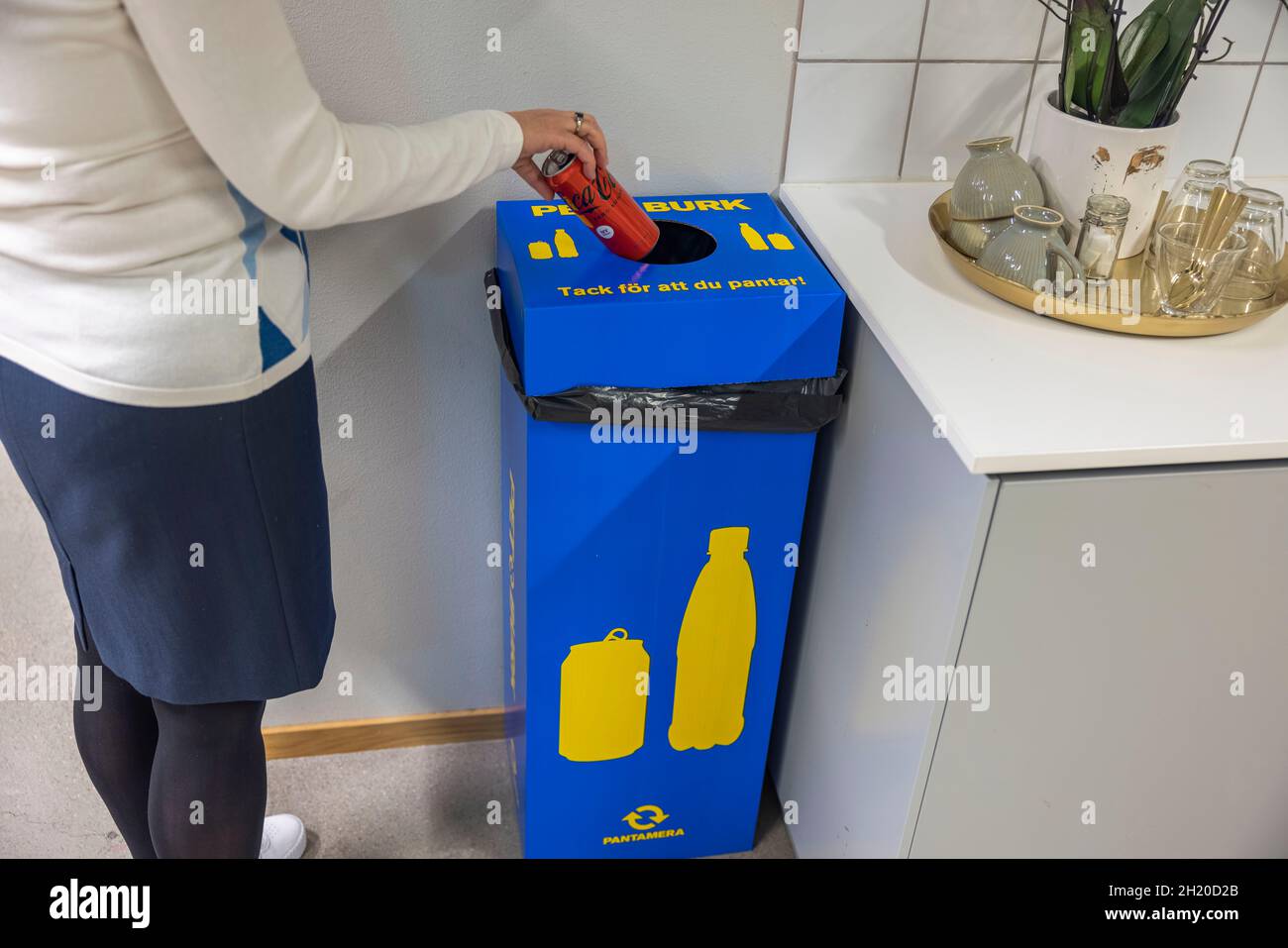 Nahaufnahme einer Frau, die leere Coca-Cola-Dose in eine große Recycling-Box für Metall und Kunststoff wirft. Schweden. Enkoping. Stockfoto