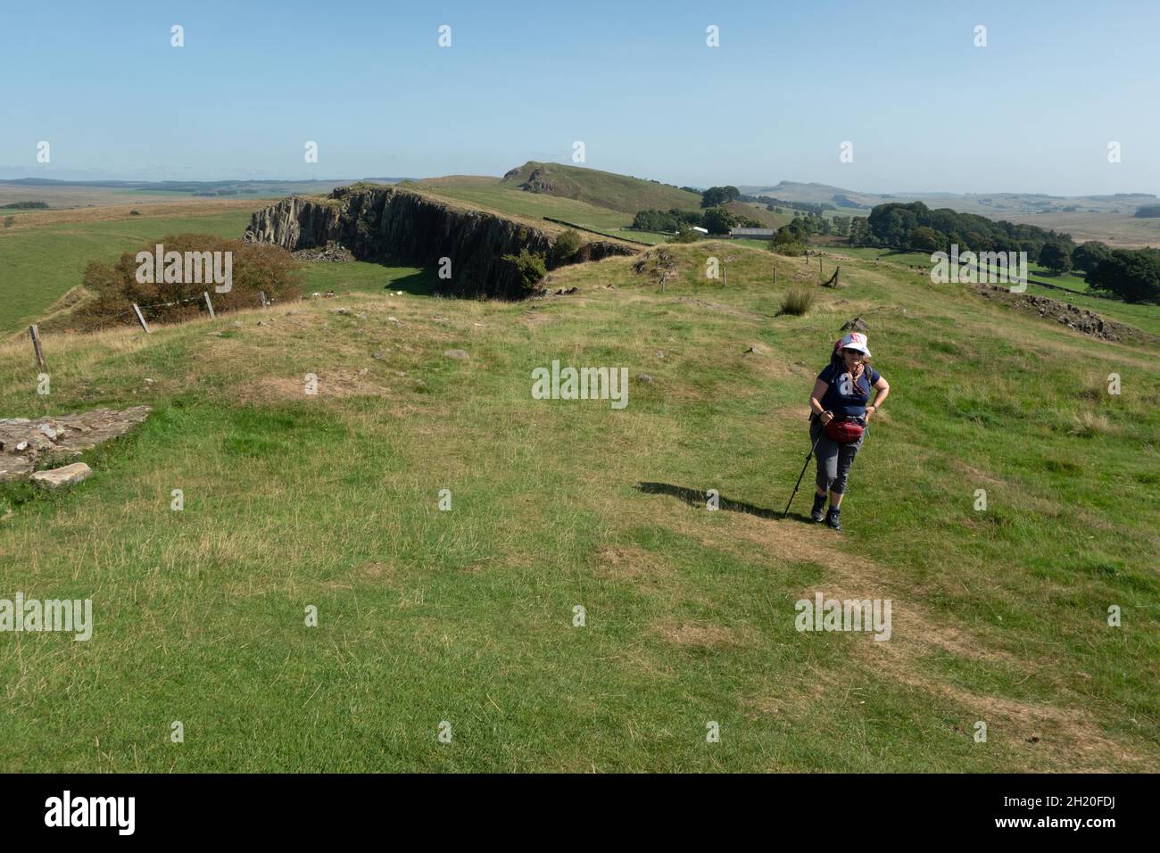 Eine alleinreisende Wanderin und Blick östlich des Cawfields Quarry auf die Hadrianmauer im Northumberland National Park England. Stockfoto