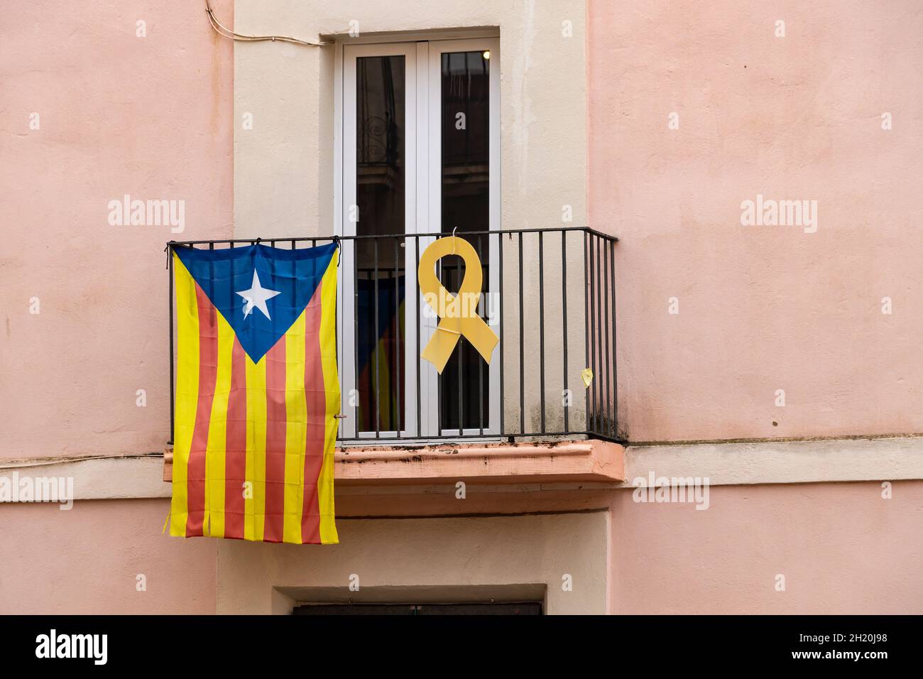 Katalanische Unabhängigkeitsfahne und gelbes Band, das an einem Fenster hängt, fordern die Unabhängigkeit Kataloniens und die Freiheit des inhaftierten Politikers Stockfoto