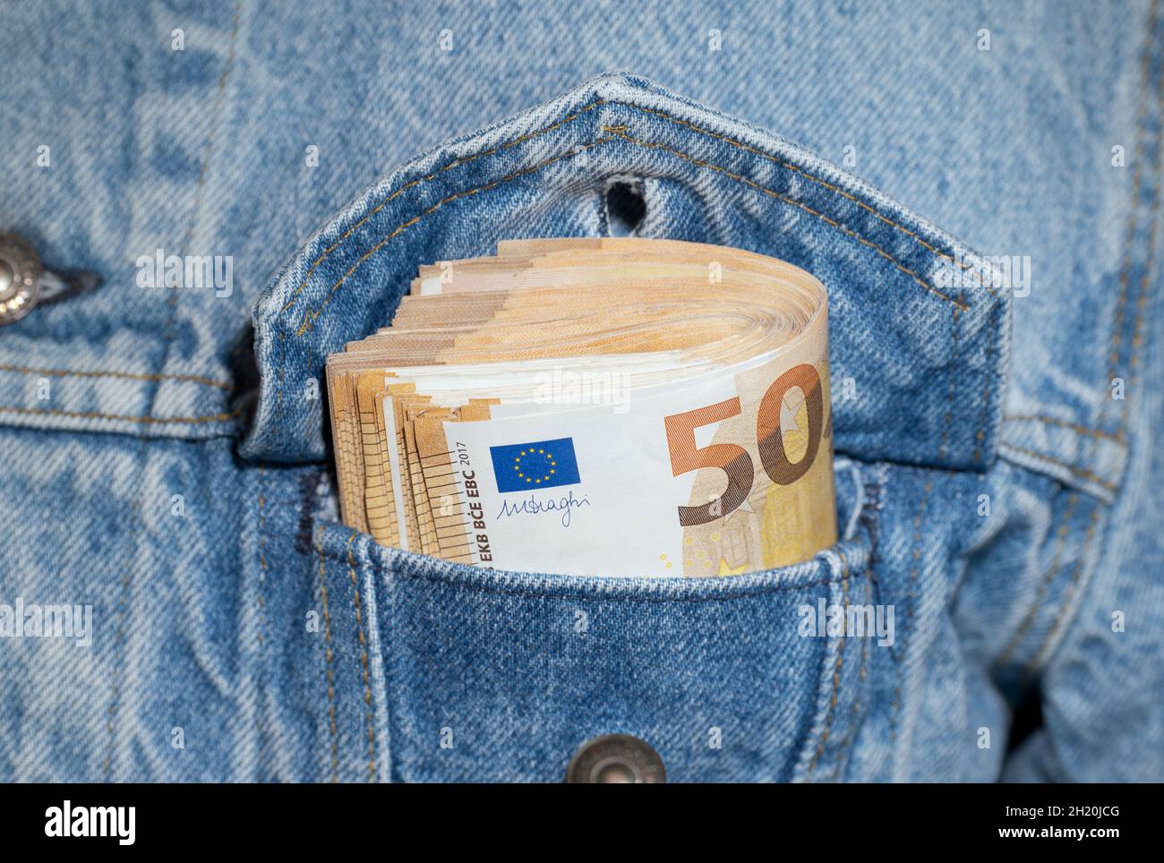 Ein Bundle mit 50-Euro-Banknoten in der Tasche einer Jeansjacke Stockfoto