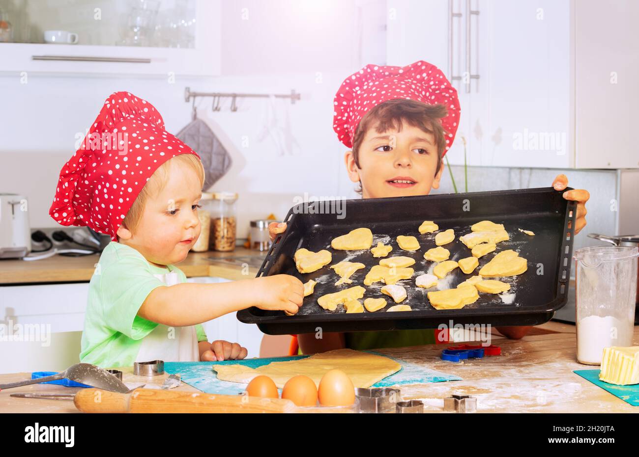 Jungen setzen Kekse auf das Backblech und bereiten das Backen vor Stockfoto
