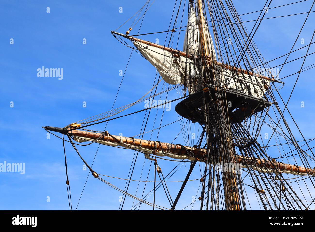 Nahaufnahme eines Mastes mit abgesenkten Segeln auf einem vollgetakelten Segelschiff. Stockfoto