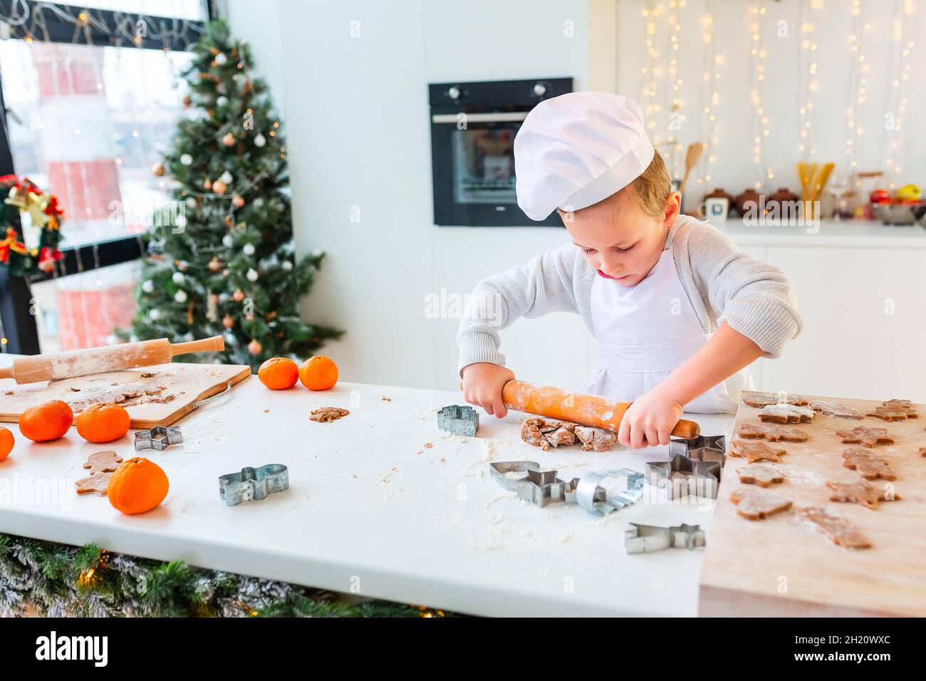 Netter kleiner Junge, der Lebkuchen macht, Kekse aus Lebkuchenteig ...