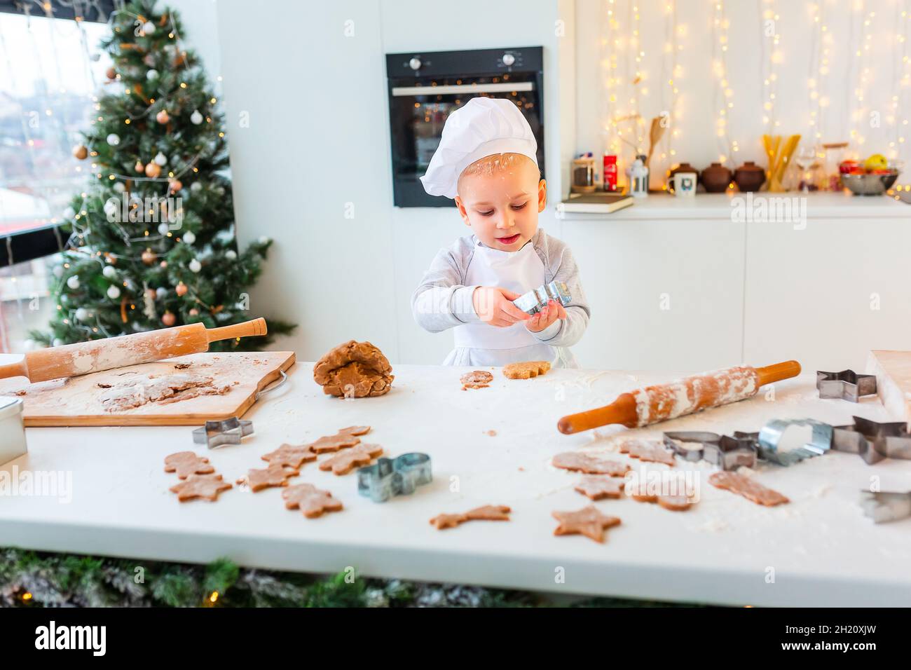 Netter kleiner Junge, der Lebkuchen macht, Kekse aus Lebkuchenteig ...