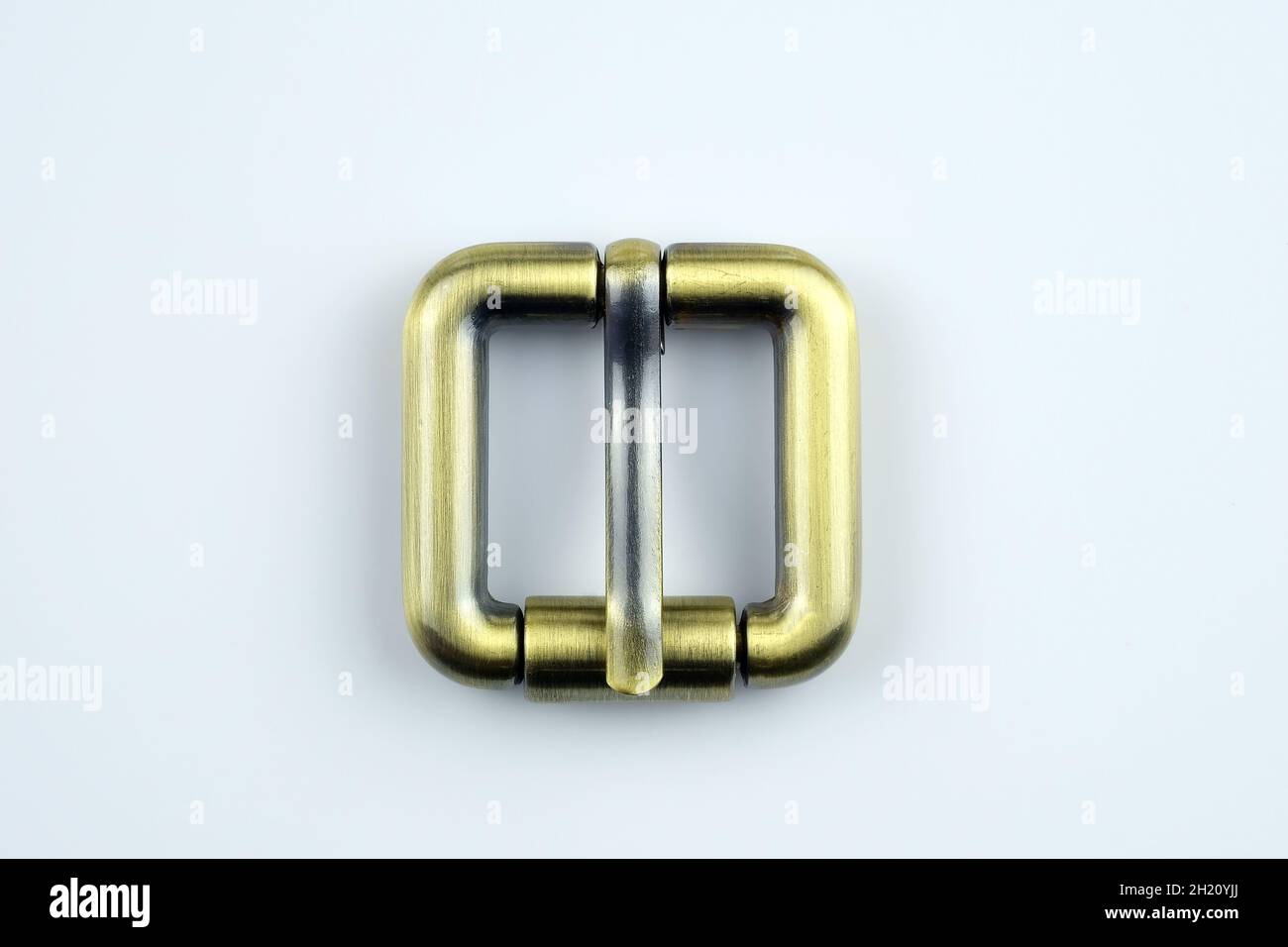 Quadratische Bronzeschnalle mit flacher Zunge auf weißem Hintergrund. Metallbeschläge für die Herstellung von Bändern. Hochwertiges Nähzubehör. Beutelbock Stockfoto