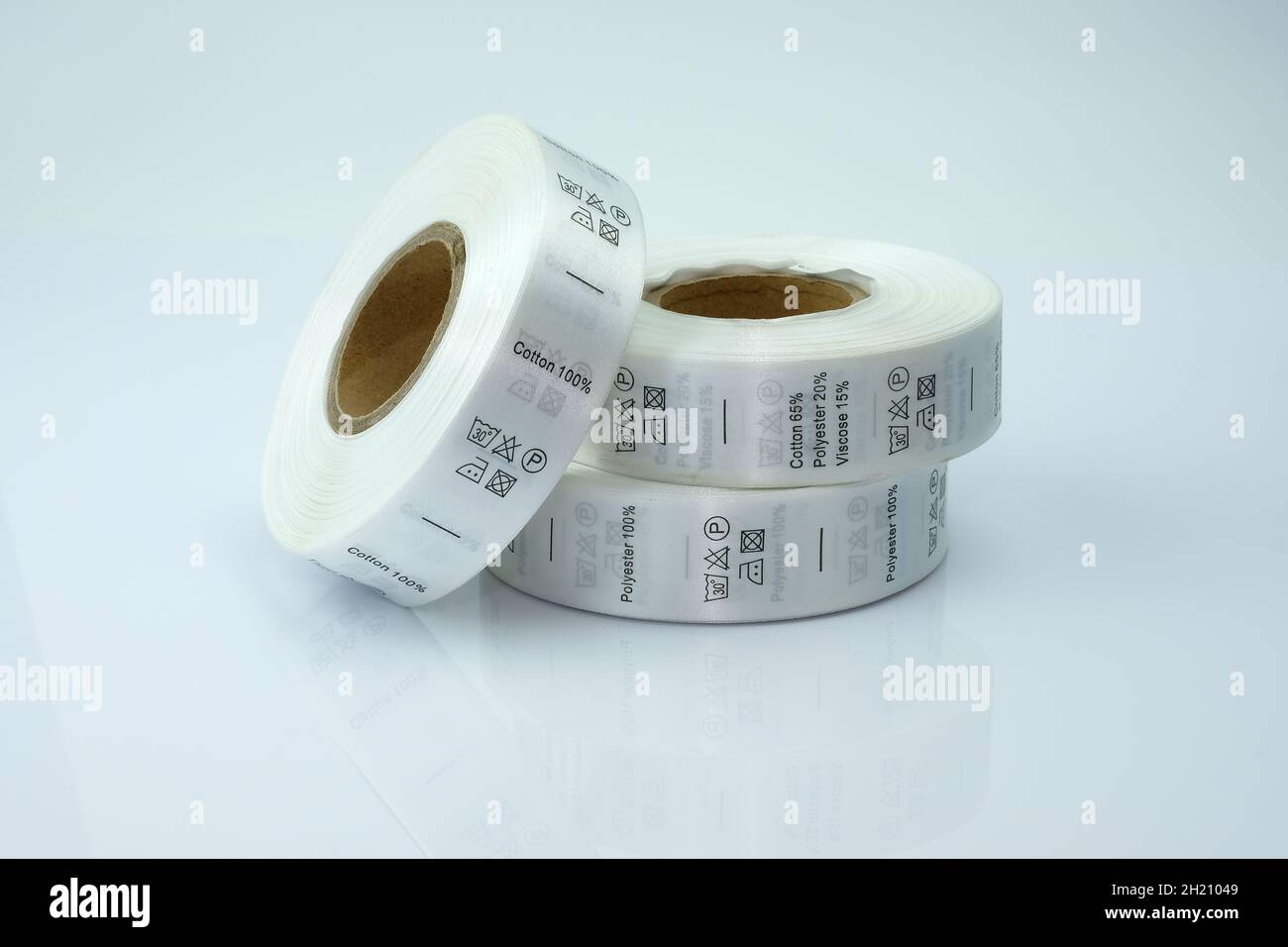 Skein Tags für Kleidung, Satinband mit Symbolen für die Verwendung von Kleidung. Weiße Skeins, eine Bandrolle mit Informationen zum Waschen und Stoffbezug Stockfoto