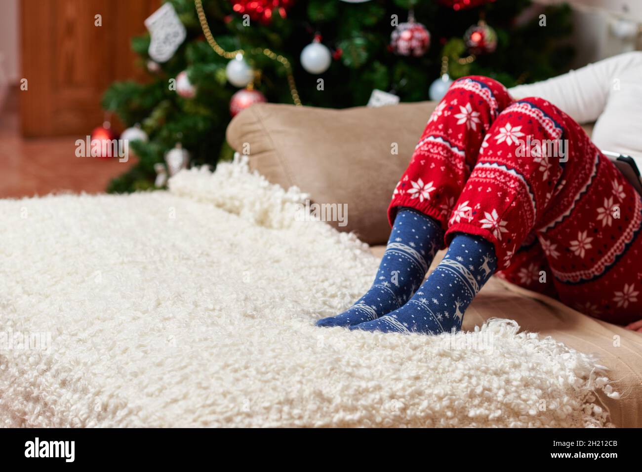 Person mit Weihnachtssocken und Schlafanzug Stockfoto