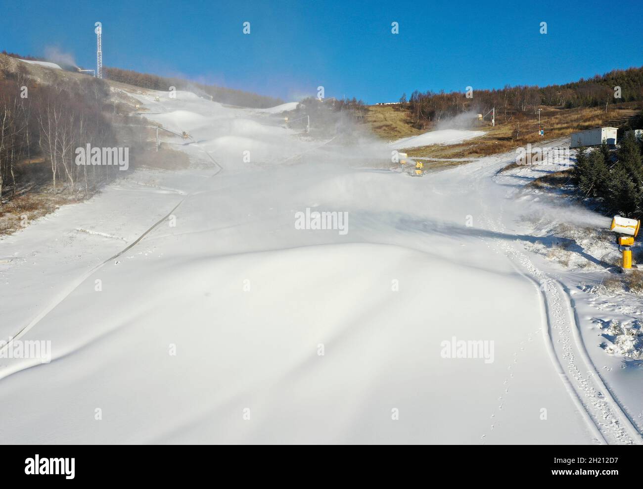 Zhangjiakou. Oktober 2021. Das Luftbild, das am 19. Oktober 2021 aufgenommen wurde, zeigt Beschneiungsmaschinen, die auf einem Skifeld im Bezirk Chongli der Stadt Zhangjiakou in der nordchinesischen Provinz Hebei arbeiten. Die Skigebiete in der Wettbewerbszone Zhangjiakou haben begonnen, künstlichen Schnee zu machen, um sich auf die bevorstehenden Olympischen Winterspiele 2022 in Peking vorzubereiten. Quelle: Wu Diansen/Xinhua/Alamy Live News Stockfoto
