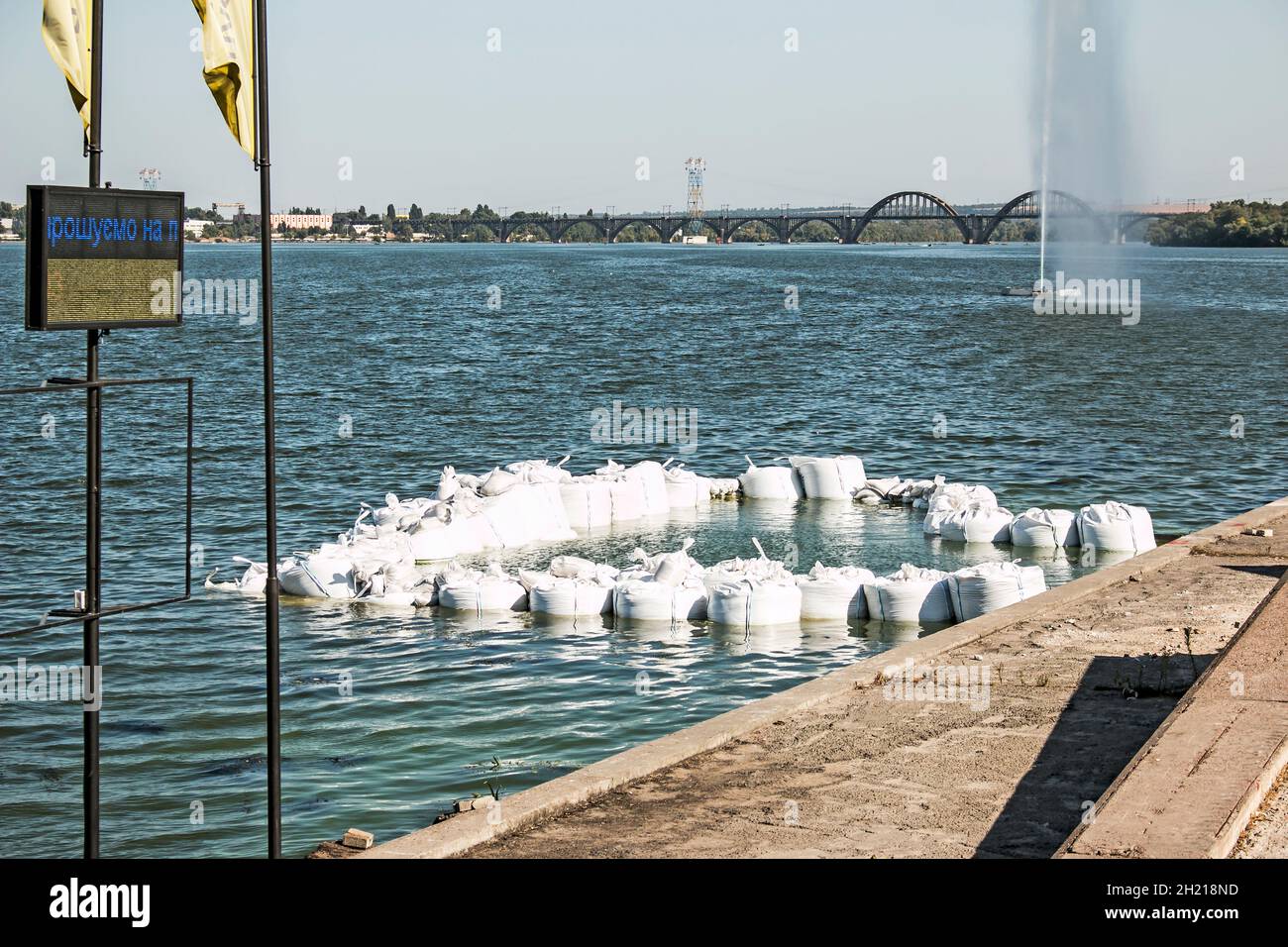 Bau des Fundaments für einen Pier am Fluss. Big Bags mit schweren Steinen werden an der Küste angelegt. Stockfoto