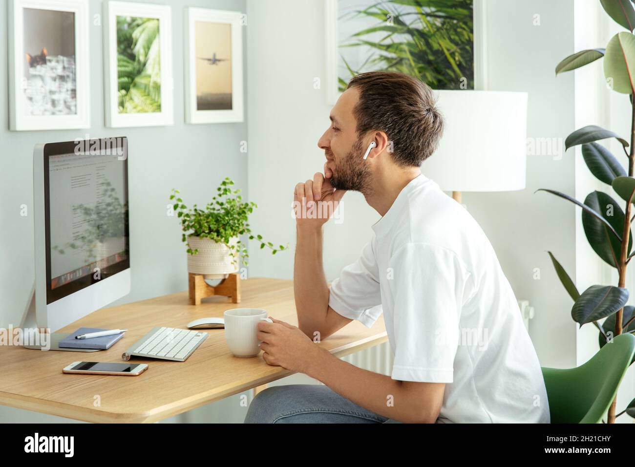 Nachdenklicher Mann schaut von zu Hause aus auf die Computermonitorarbeit. Freiberuflicher Programmierer Kerl am Arbeitsplatz Stockfoto