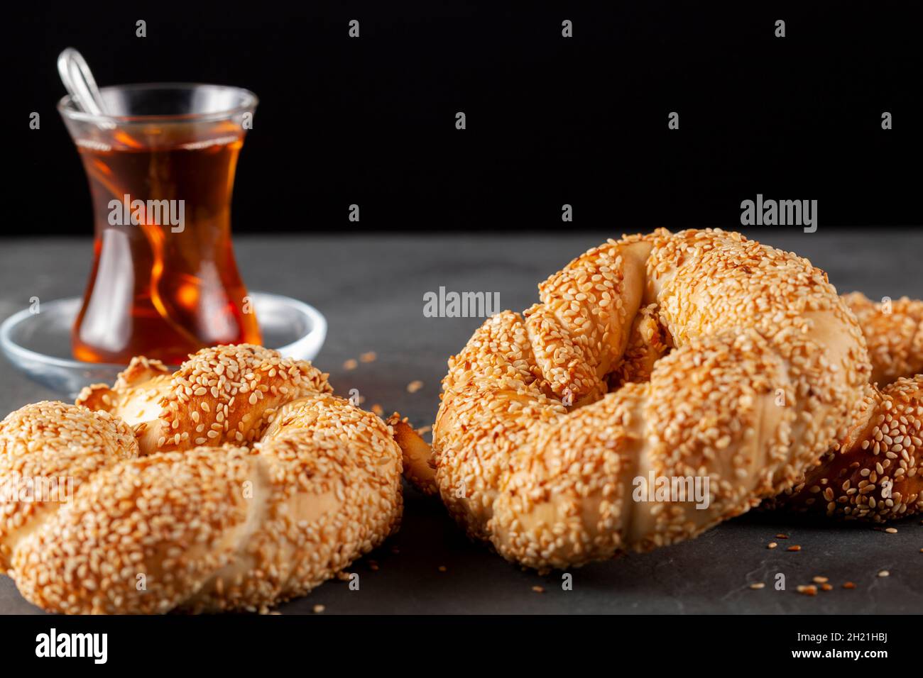 Köstlicher türkischer Bagel mit Sesamsamen, bekannt als Susamli simit. Dunkler Hintergrund krümelig frisch aus Backwaren serviert auf Stein mit einer Tasse schwarz Stockfoto