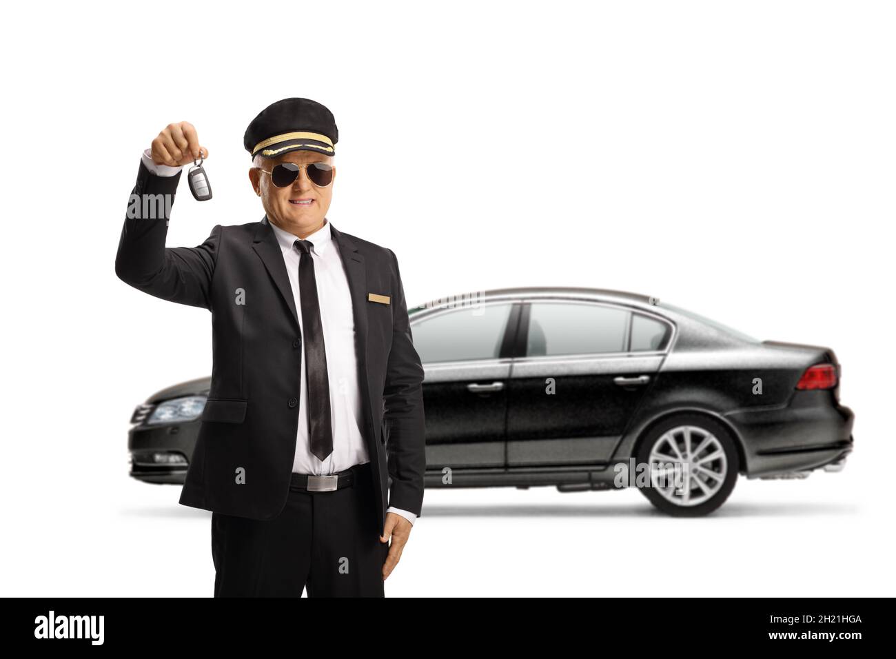 Reifer Chauffeur in Uniform mit Sonnenbrille, der einen Autoschlüssel aus einem schwarzen, auf weißem Hintergrund isolierten Auto hält Stockfoto