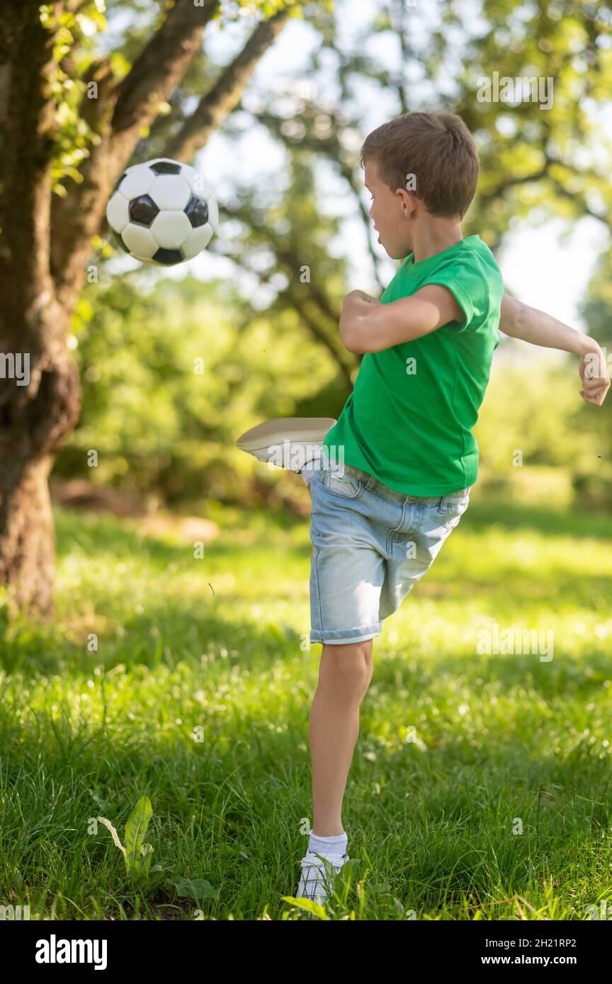 Energischer Junge tritt den Fußball zurück. Stockfoto