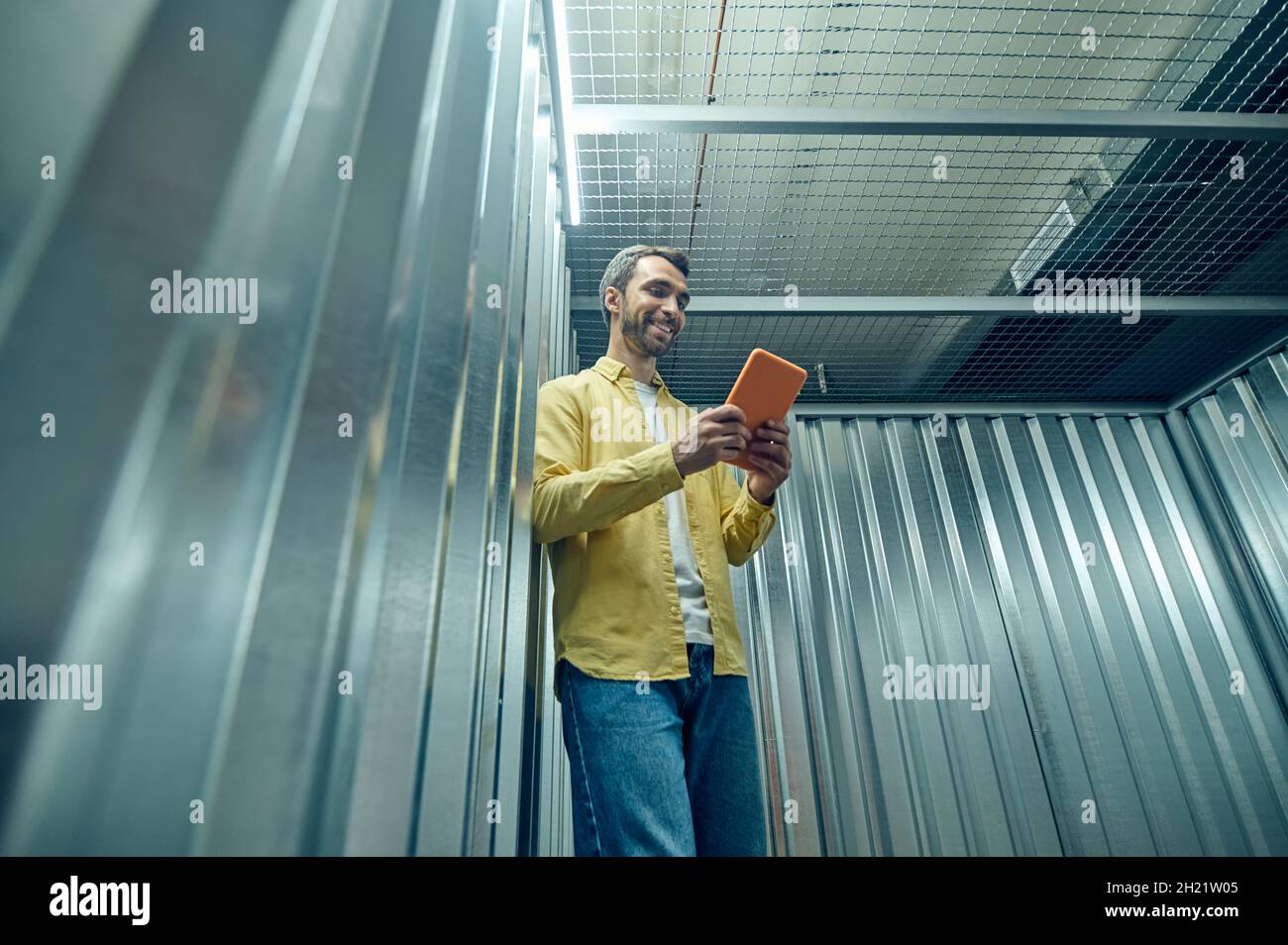 Optimistischer junger Mann, der Tablet in der Garage ansieht Stockfoto