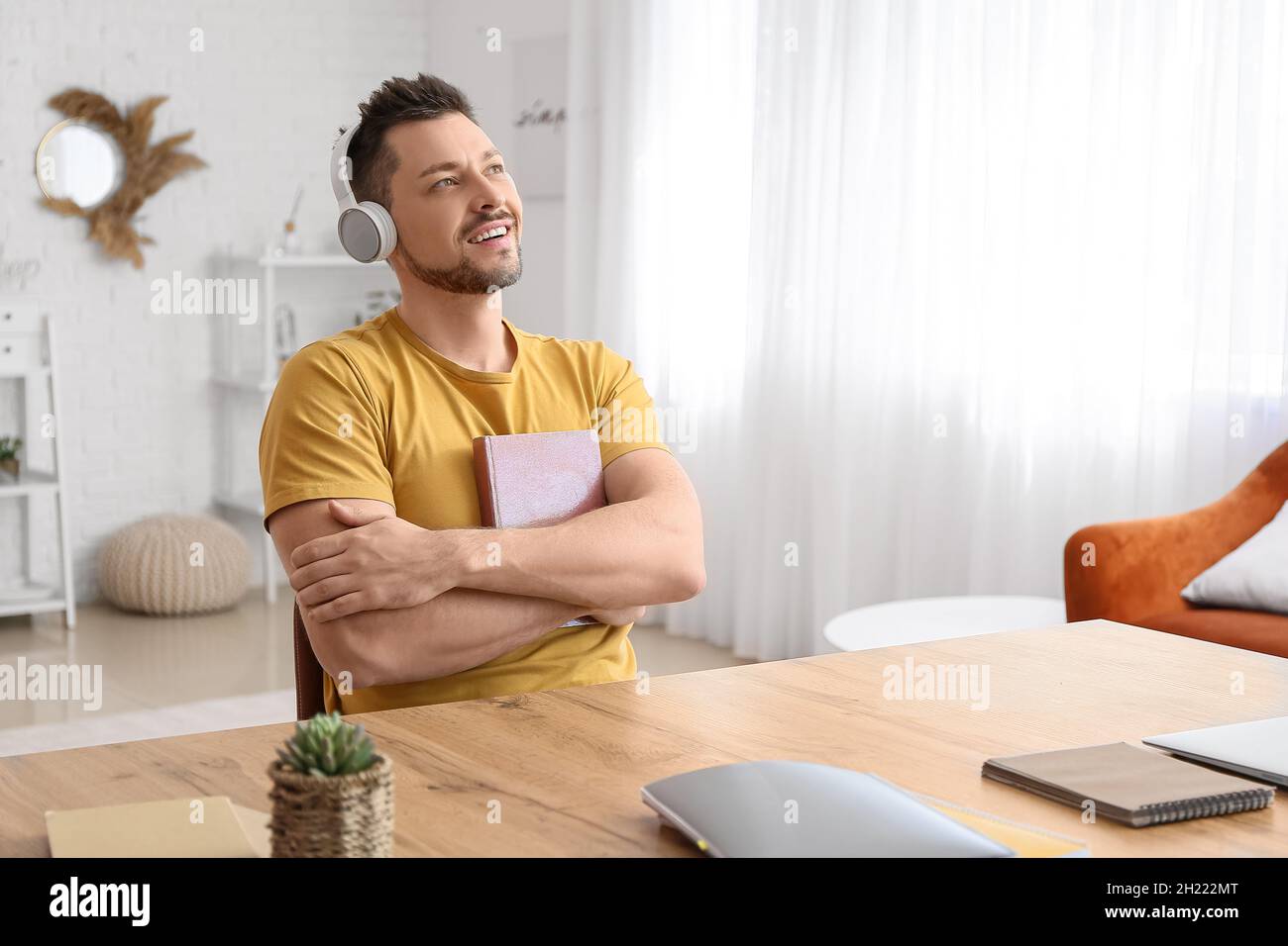 Mann mit Kopfhörern hört Hörbuch am Tisch Stockfoto