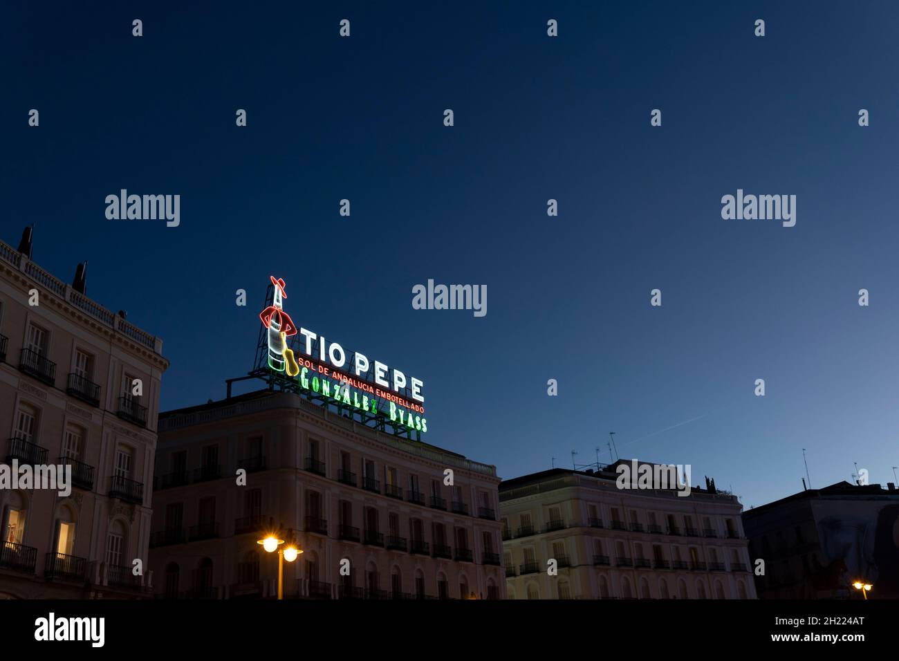 Das Wahrzeichen von Tío Pepe, eine Werbung für Tío Pepe Sherry, beleuchtet die Puerta del Sol bei Sonnenuntergang in Madrid, Spanien. Stockfoto
