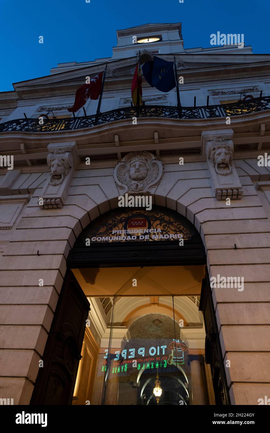 Das Neonschild Tío Pepe spiegelt sich am Eingang der Casa de Correos, dem Büro des Präsidenten der Gemeinschaft Madrid, an der Puerta wider Stockfoto
