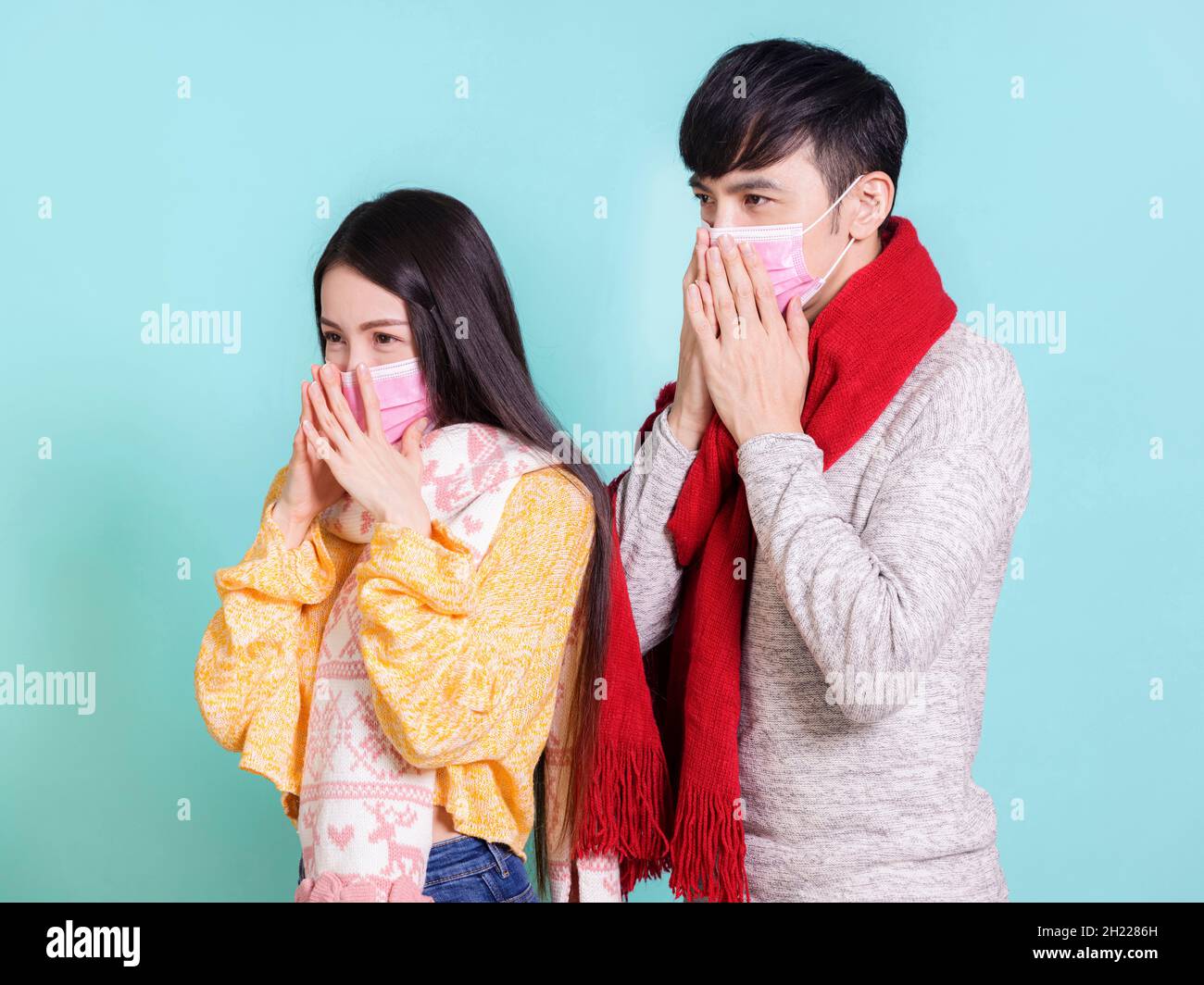 Junges Paar mit medizinischen Masken und legerer Winterkleidung Stockfoto