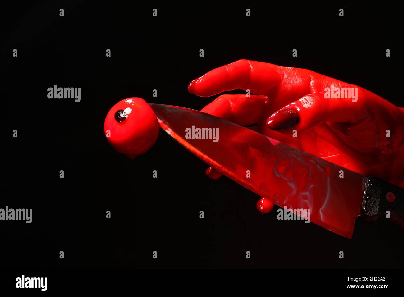 Hand mit blutbeflecktem Messer und Augenball auf schwarzem Hintergrund Stockfoto