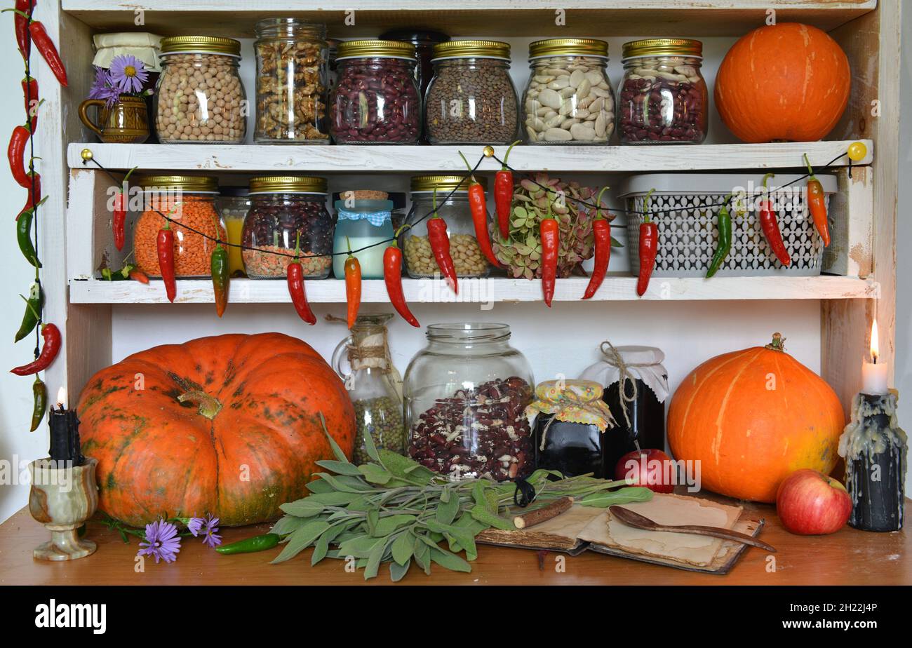 Vintage Küche Stillleben mit trockenen Bohnen in Glasflaschen, trockener Paprika, frischem Gemüse, Kürbis. Provenzalische, ländliche Atmosphäre Stockfoto