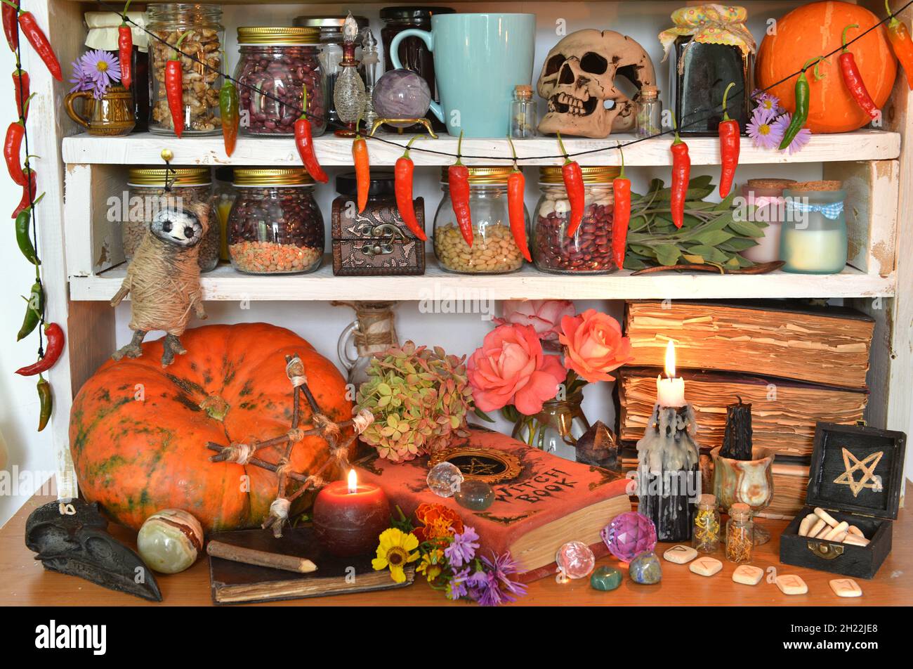 Vintage Küche Stillleben mit Hexerei Ritual obects, mystische Bücher von Zaubersprüchen, Flasche Trank, Schädel, Kürbis und brennende Kerze auf Holz zählen Stockfoto