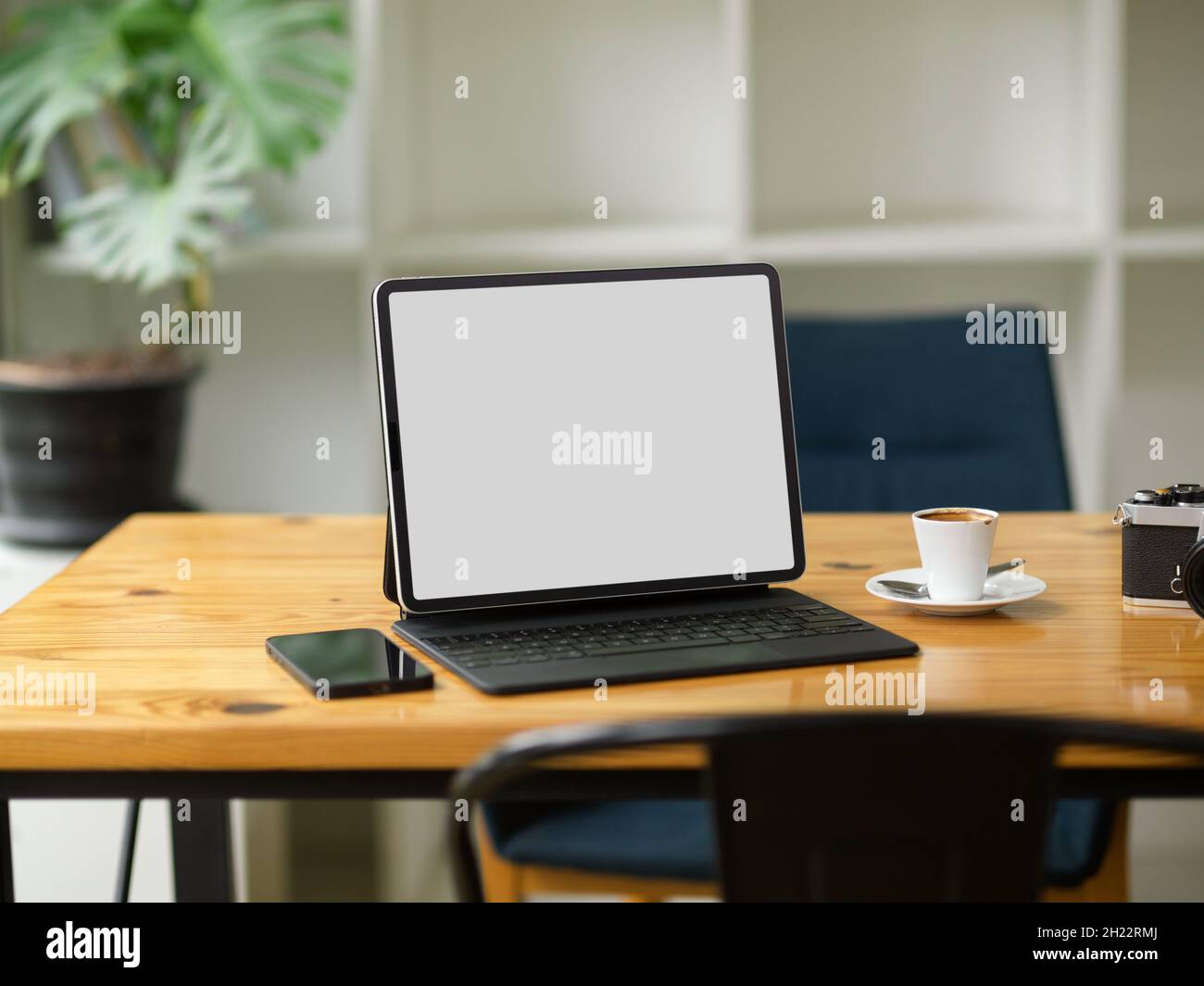 Moderner tragbarer Tablet-Computer mit magischer Tastatur in leerem Bildschirm, Mockup-Stand auf Holztisch im Café Stockfoto